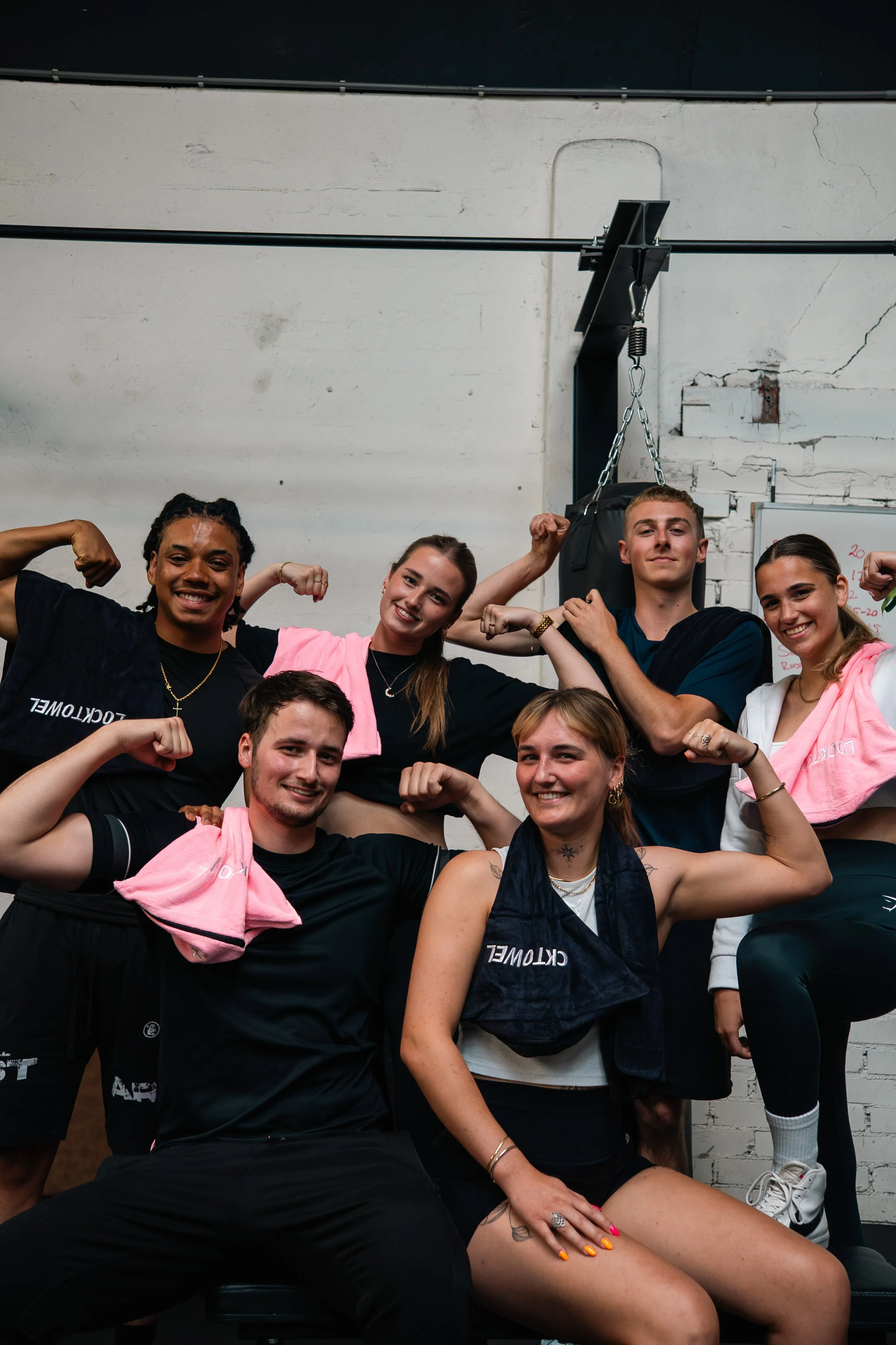 Een groep mensen in sportkleding die poseren en biceps tonen in een sportschool. Sporthanddoek. Locktowel.