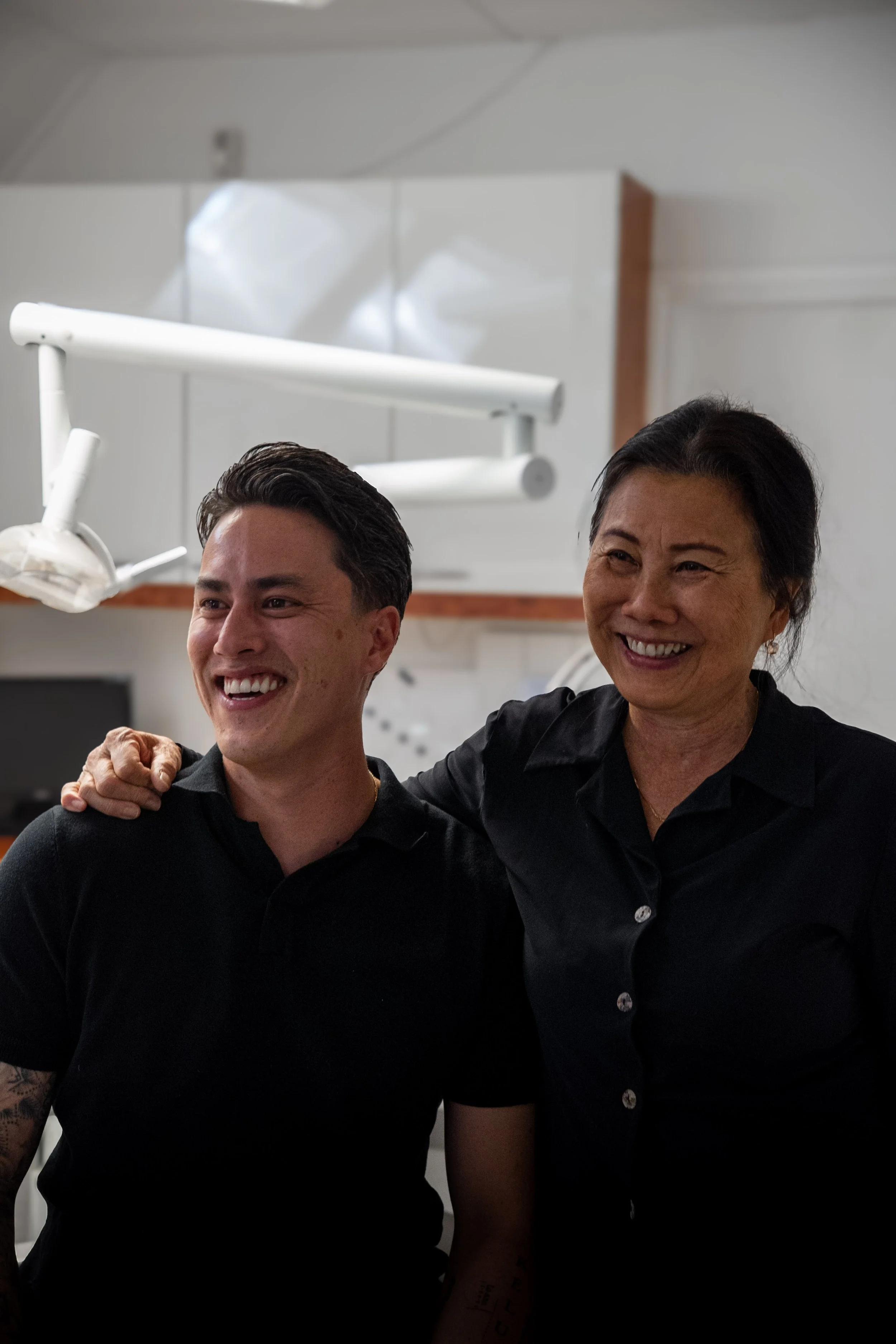 Twee mensen lachen en staan dicht bij elkaar, een van hen heeft haar arm om de schouder van de ander. Wittewel. Tandenbleken. Tandartspraktijk Oss