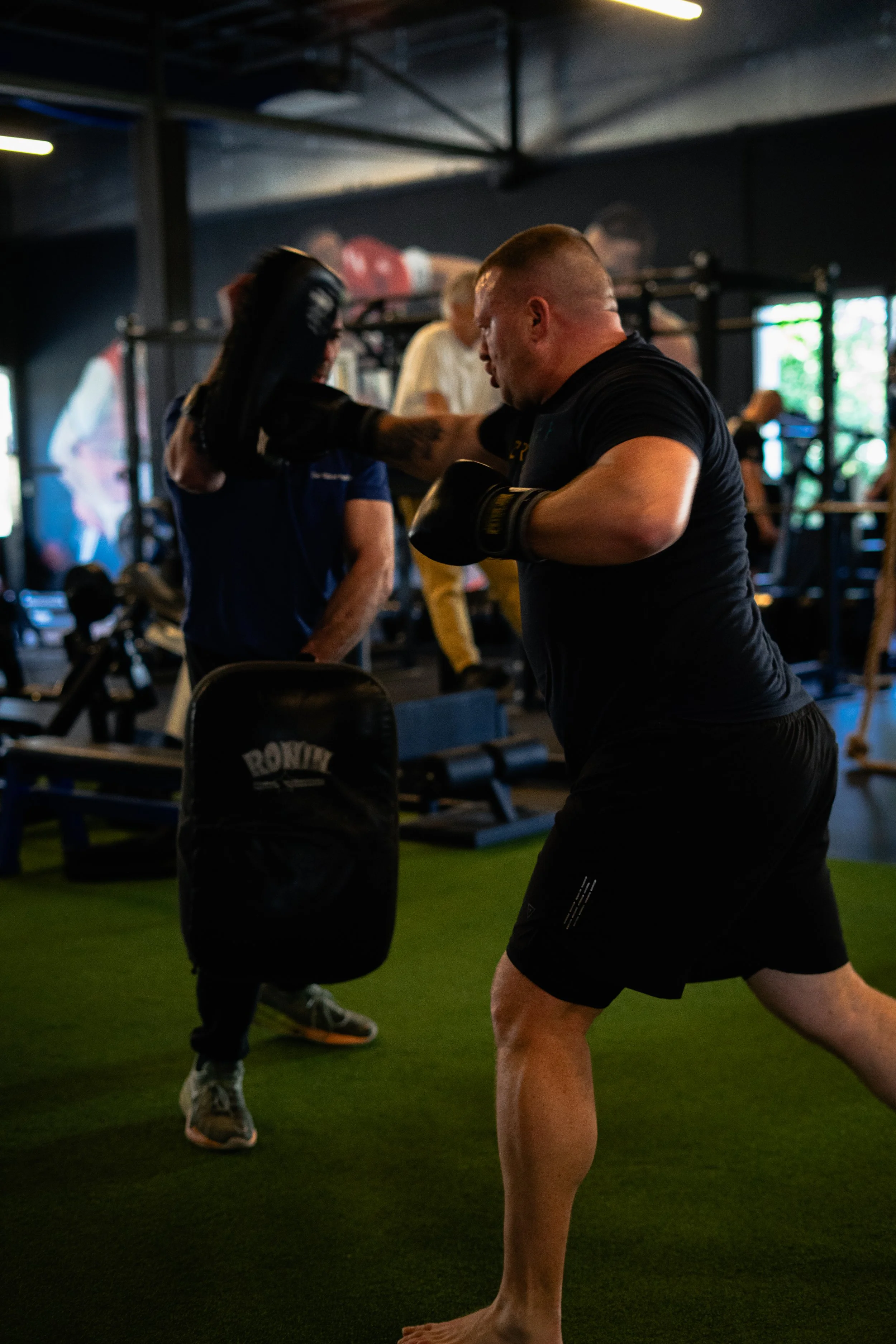 Man die een boksztechniek oefent met een trainer in een sportschool. Sportschool Emmen. Krachttraining. Boksen.