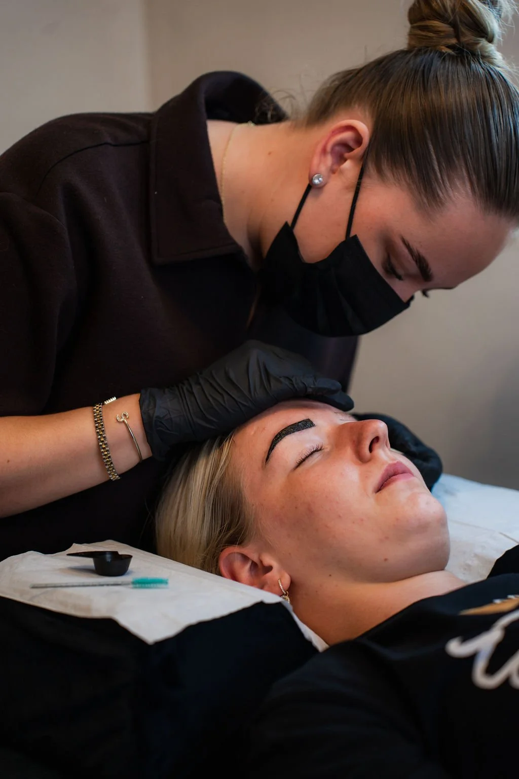 Tandarts of huidverzorgingspecialist behandelt een vrouw die ligt met gesloten ogen, ter ondersteuning van een cosmetisch of huidbehandelingsproces. Beautysalon.