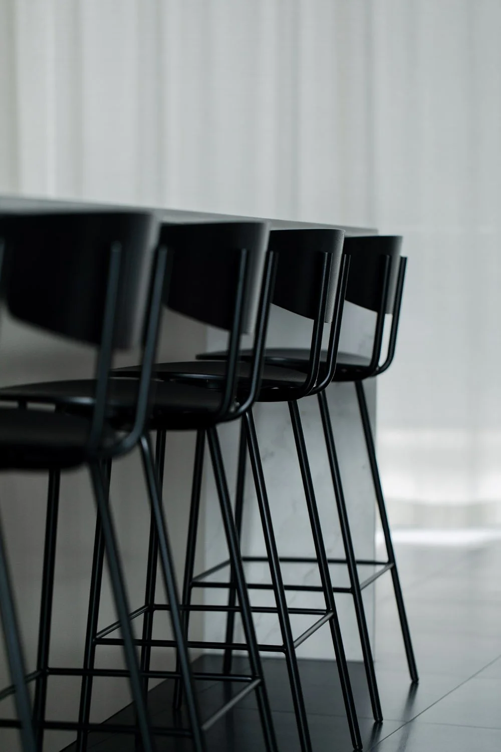 Mustat baarituolit valkoisen saarekkeen ympärillä.