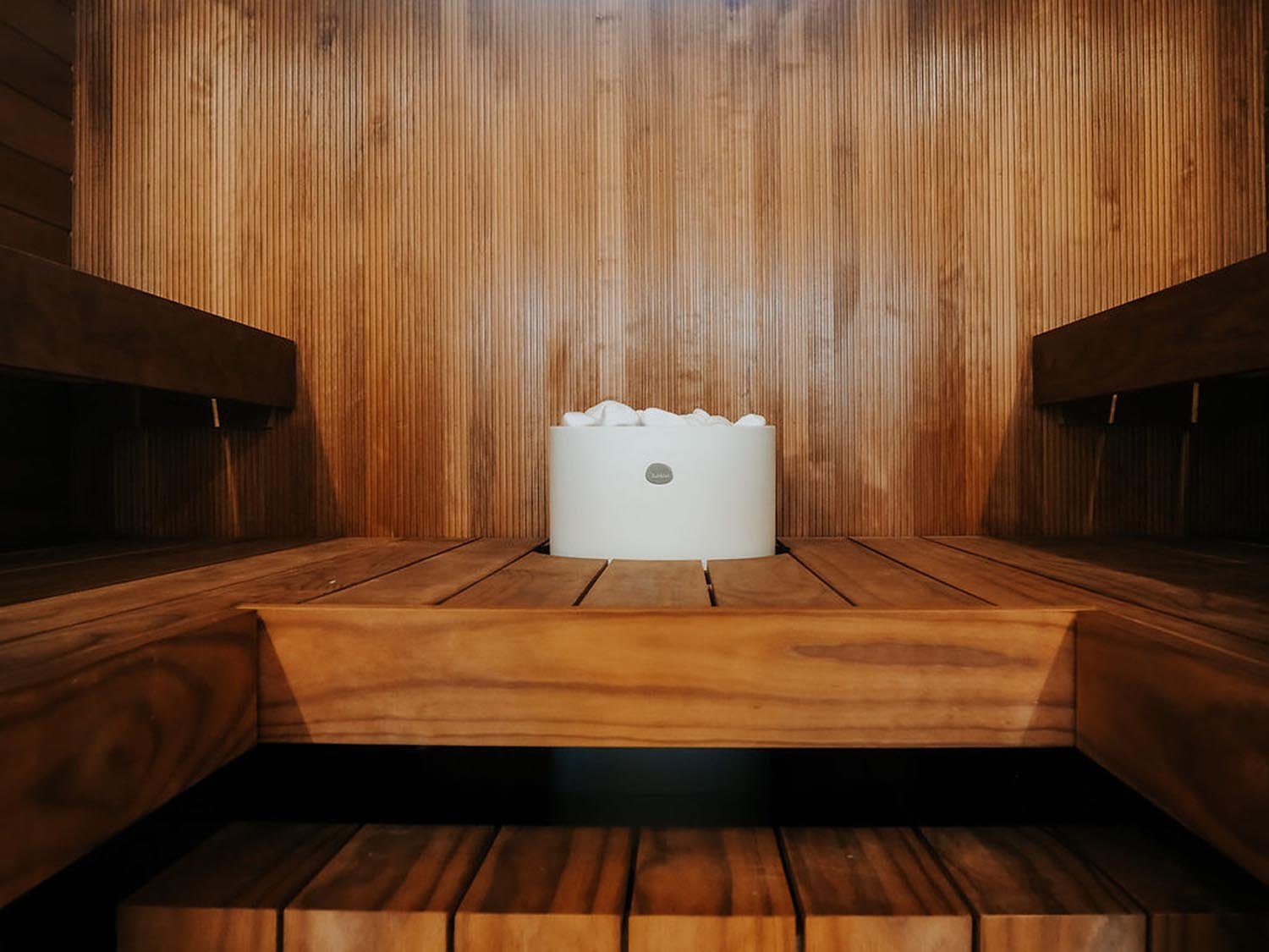 Puunvärinen sauna ja vaalea kiuas upotettuna lauteisiin.