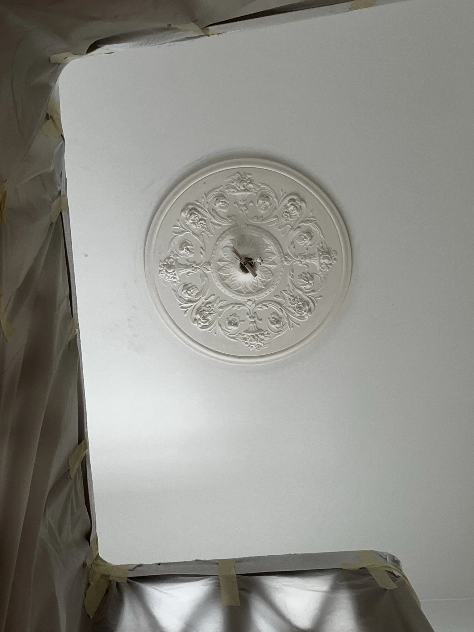 Plafond en plâtre avec moulure en relief et rosace en staff au centre.