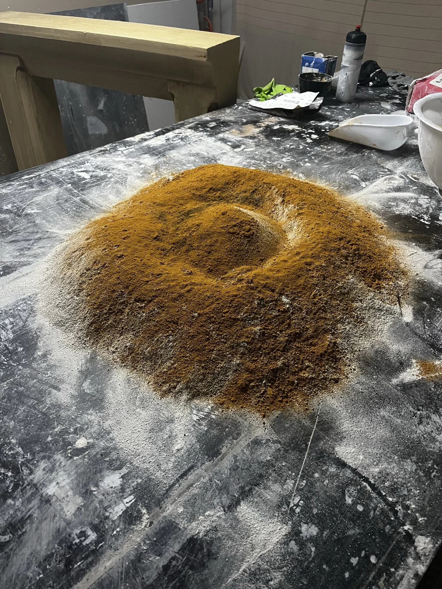 Poudre à épices ou à farine colorée en jaune-orange sur une surface recouverte de farine ou poudre, dans un environnement de cuisine ou atelier