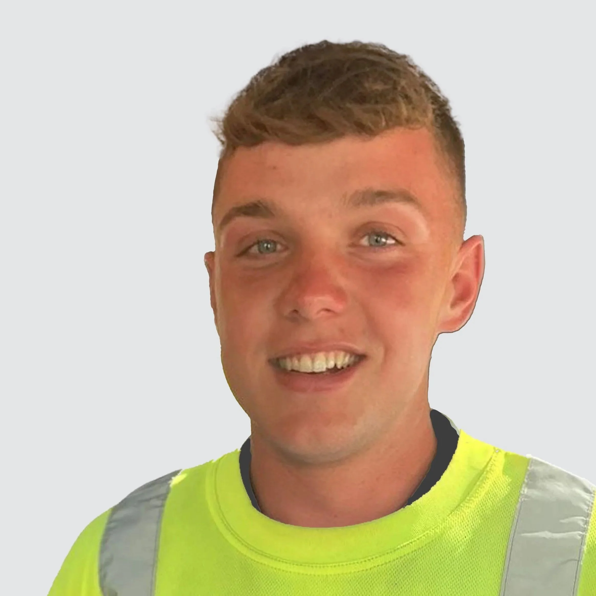 A young man with light skin, short brown hair, and blue eyes, smiling, wearing a high-visibility yellow safety vest against a plain light gray background.