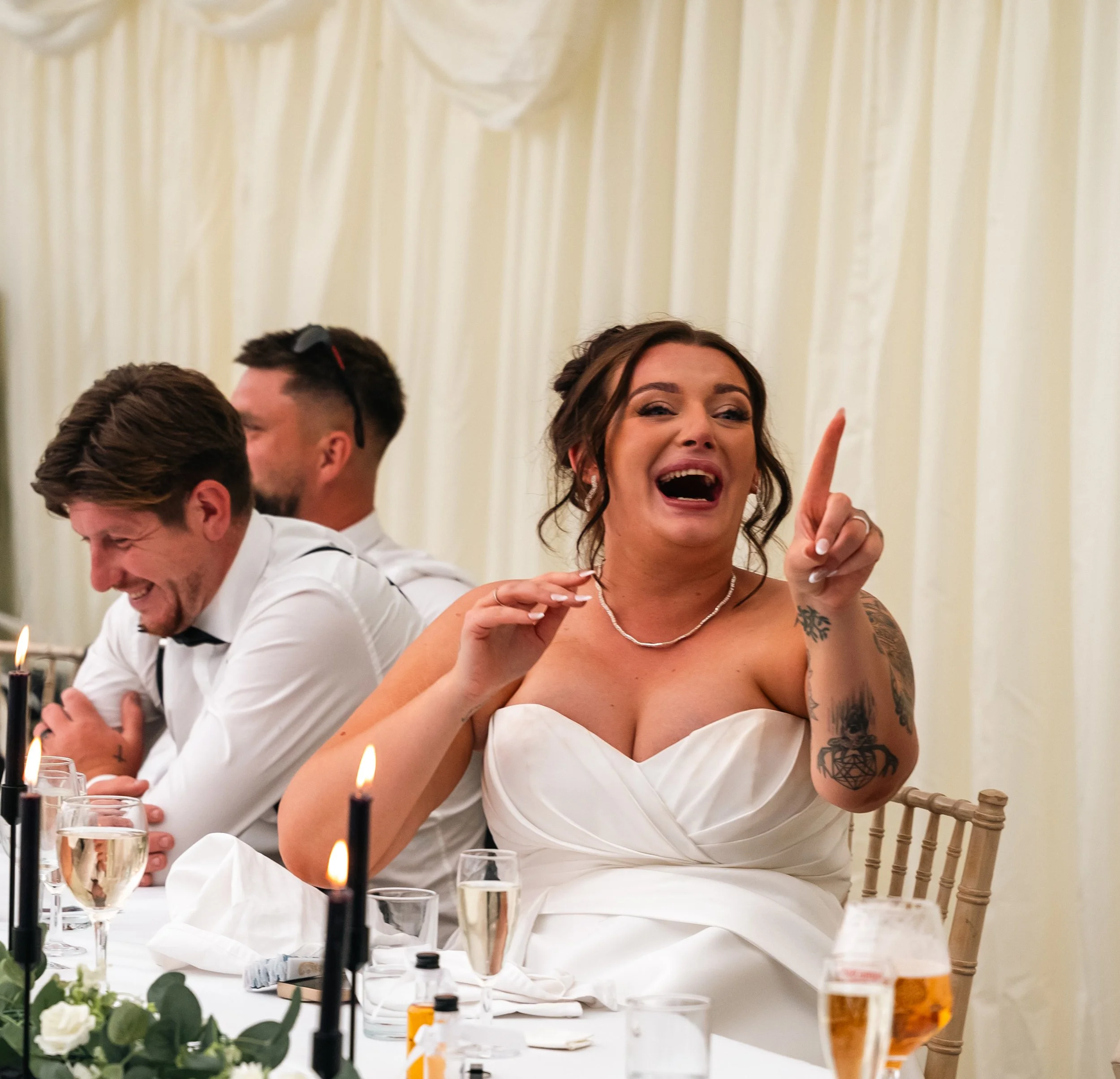 Bride at her wedding, next to her husband, both laughing at a speech at Oakhill, Cromford.