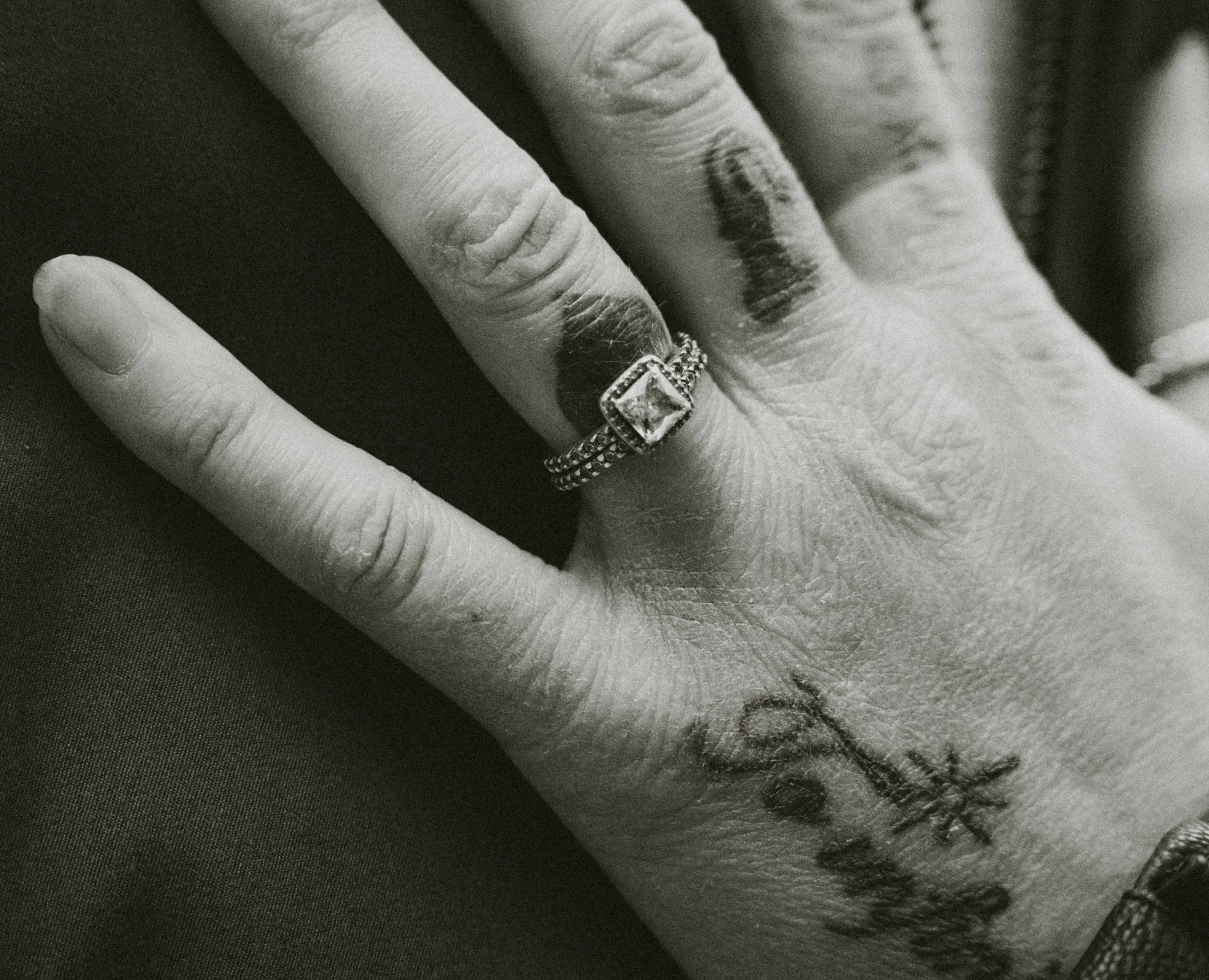 Close-up of a hand displaying a large diamond engagement ring and a wedding band with smaller diamonds on the ring finger.