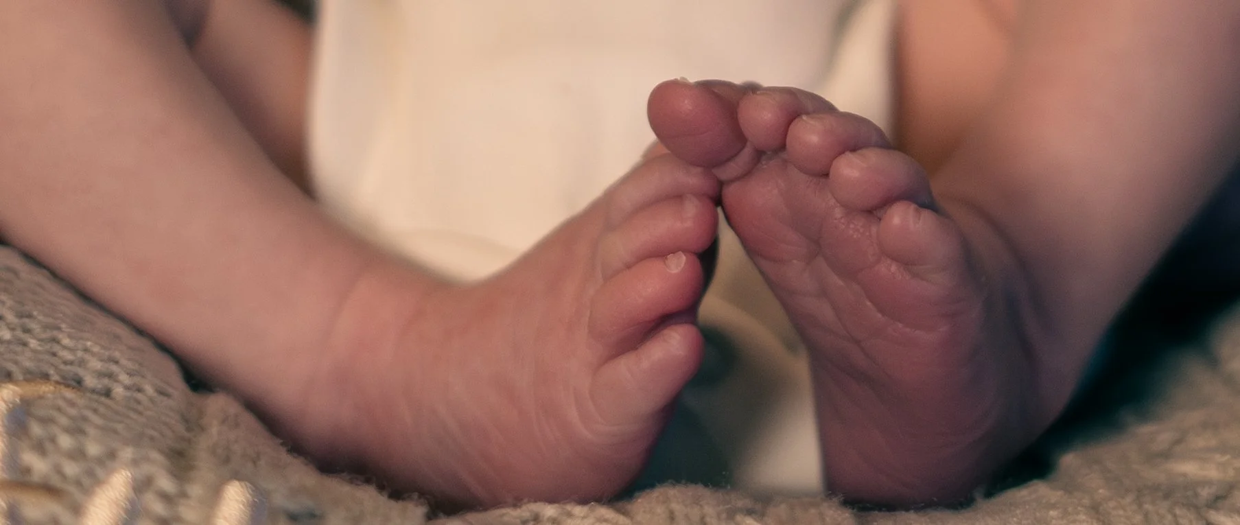 A close-up of a baby's and adult's hands touching fingertips, symbolizing connection and tenderness.