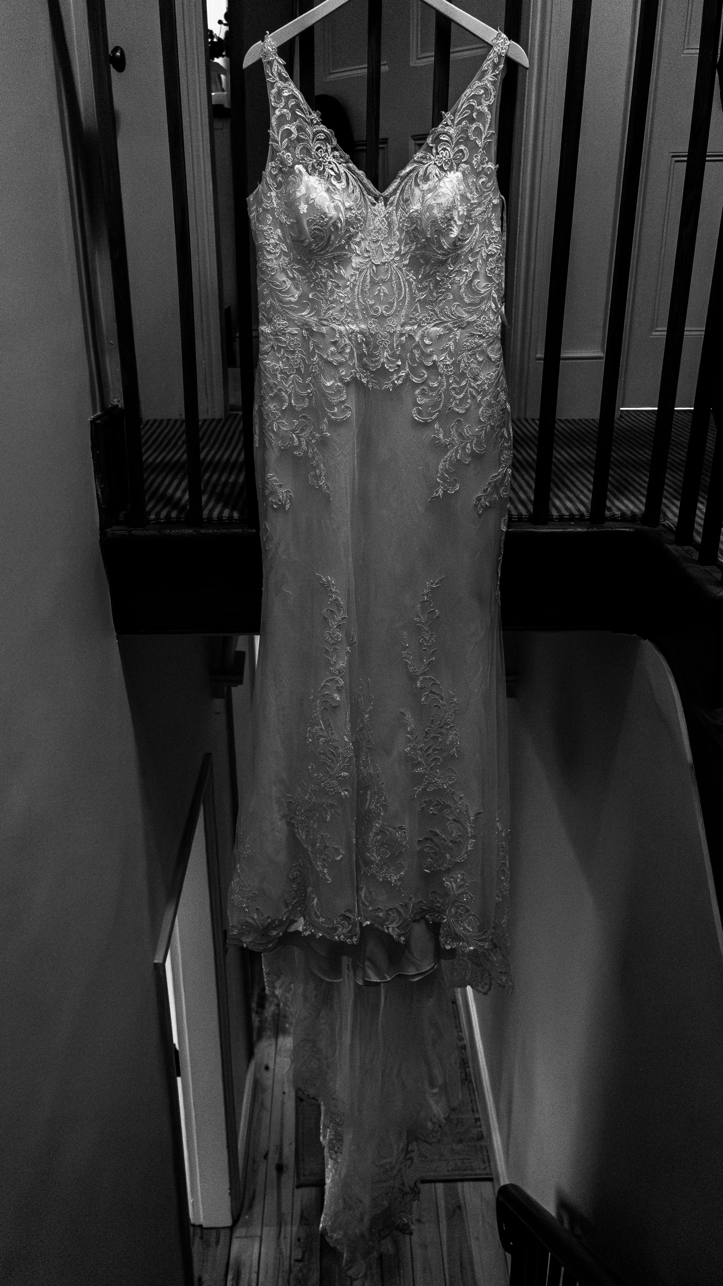 A wedding dress hanging on a wooden hanger on a staircase railing.