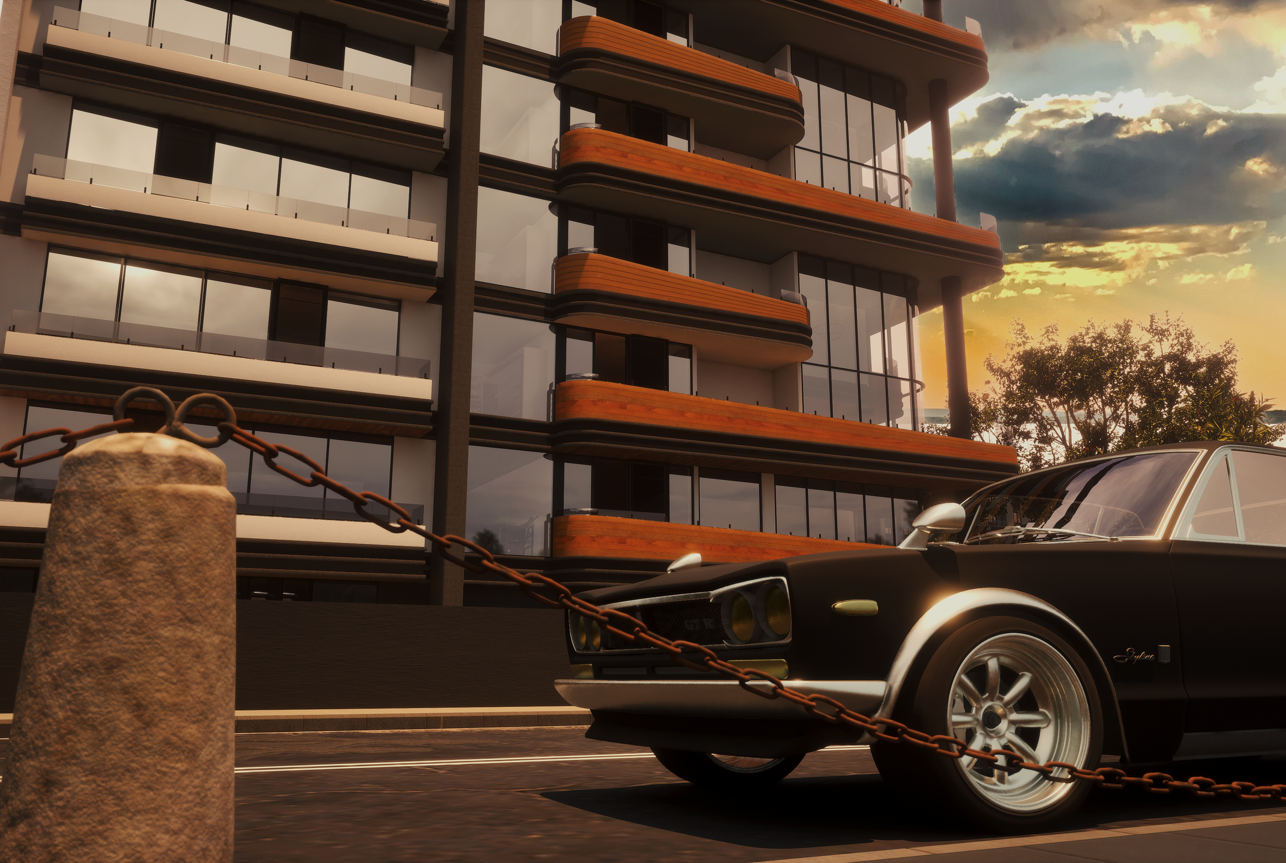 A black vintage sports car parked in front of a modern apartment building during sunset. The car is behind a rusted chain barrier connected to stone posts.