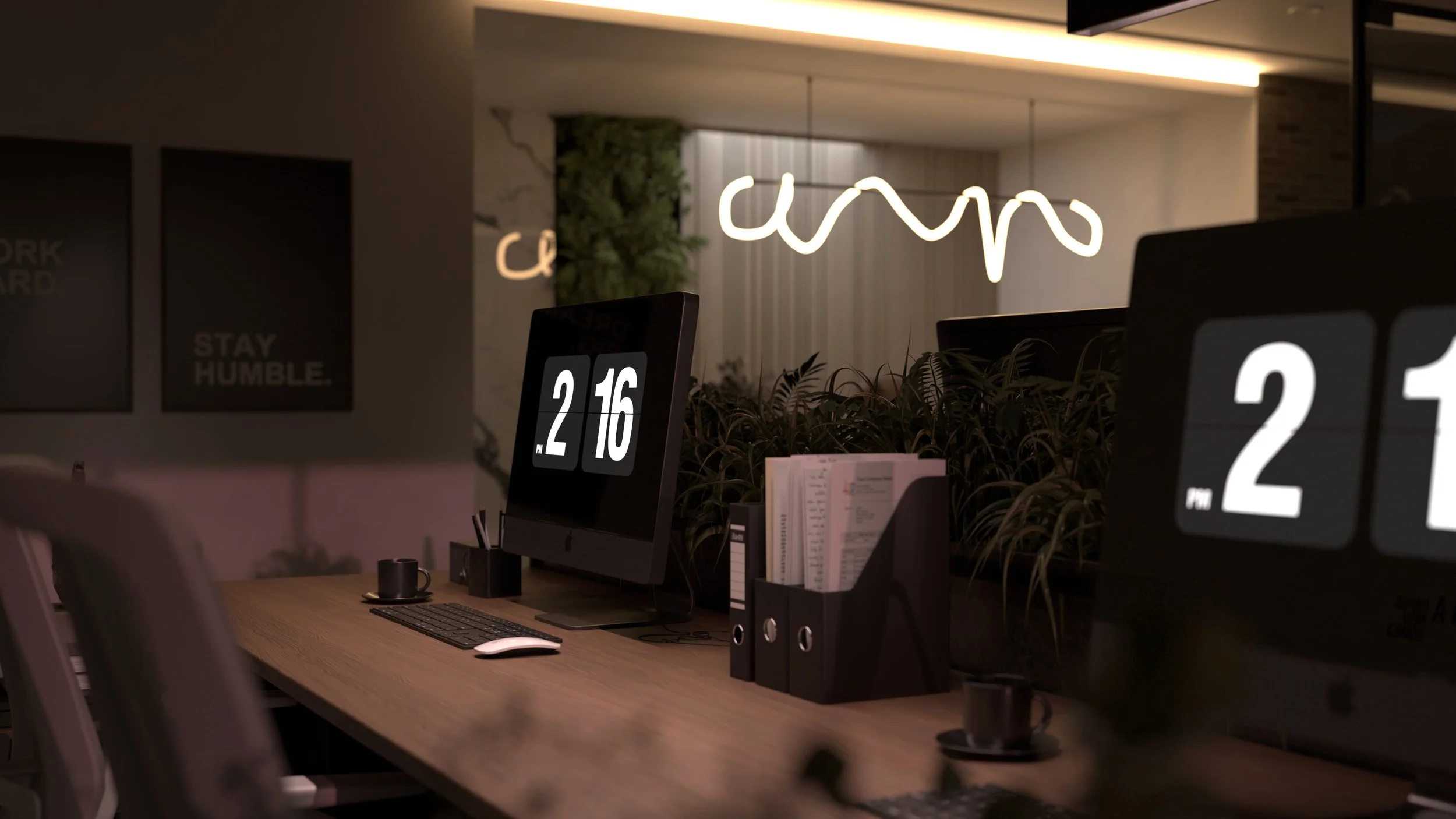 A modern office workspace with a wooden desk, two computer monitors displaying the time, a keyboard, a mouse, and some office supplies. There's a plant in the background and wall decorations, including a neon sign and framed text that says "STAY HUMB