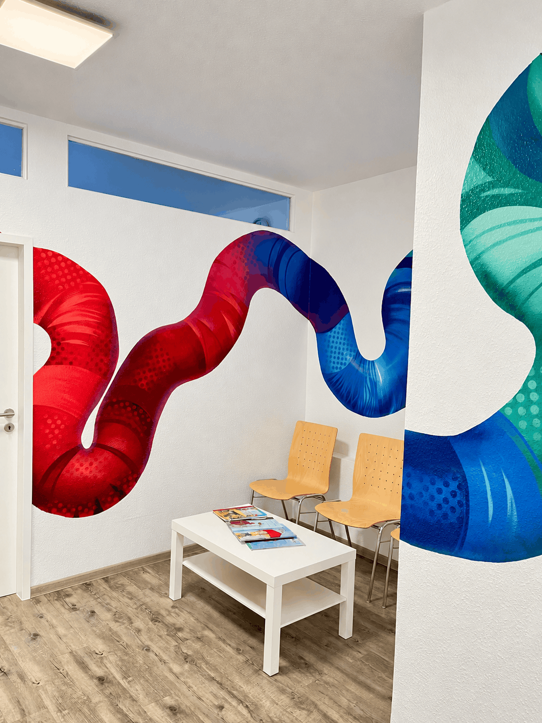 Heller Wartebereich mit buntem Wellenmural.png