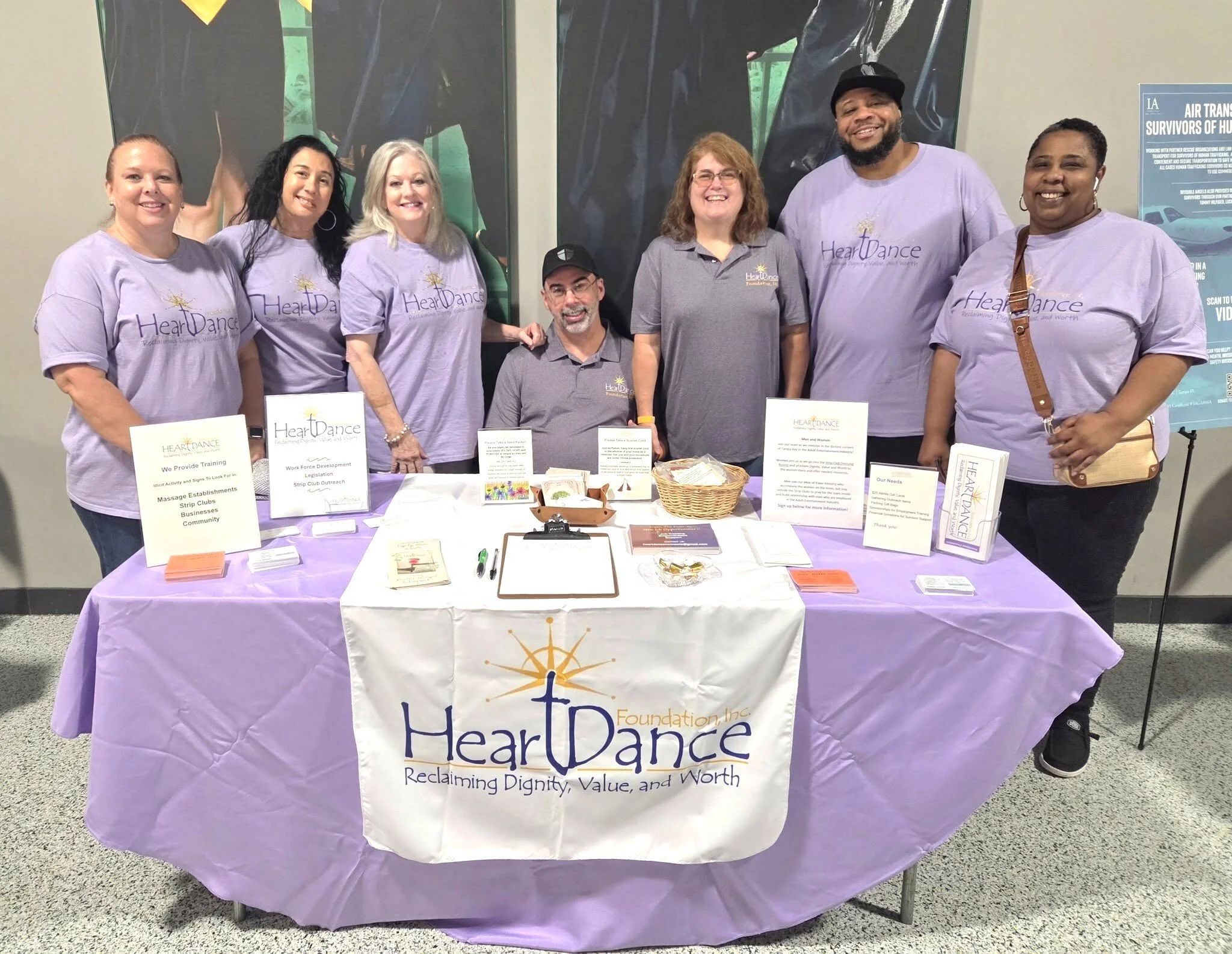 Group of seven people standing around a table with Heart Dance Foundation materials at an event