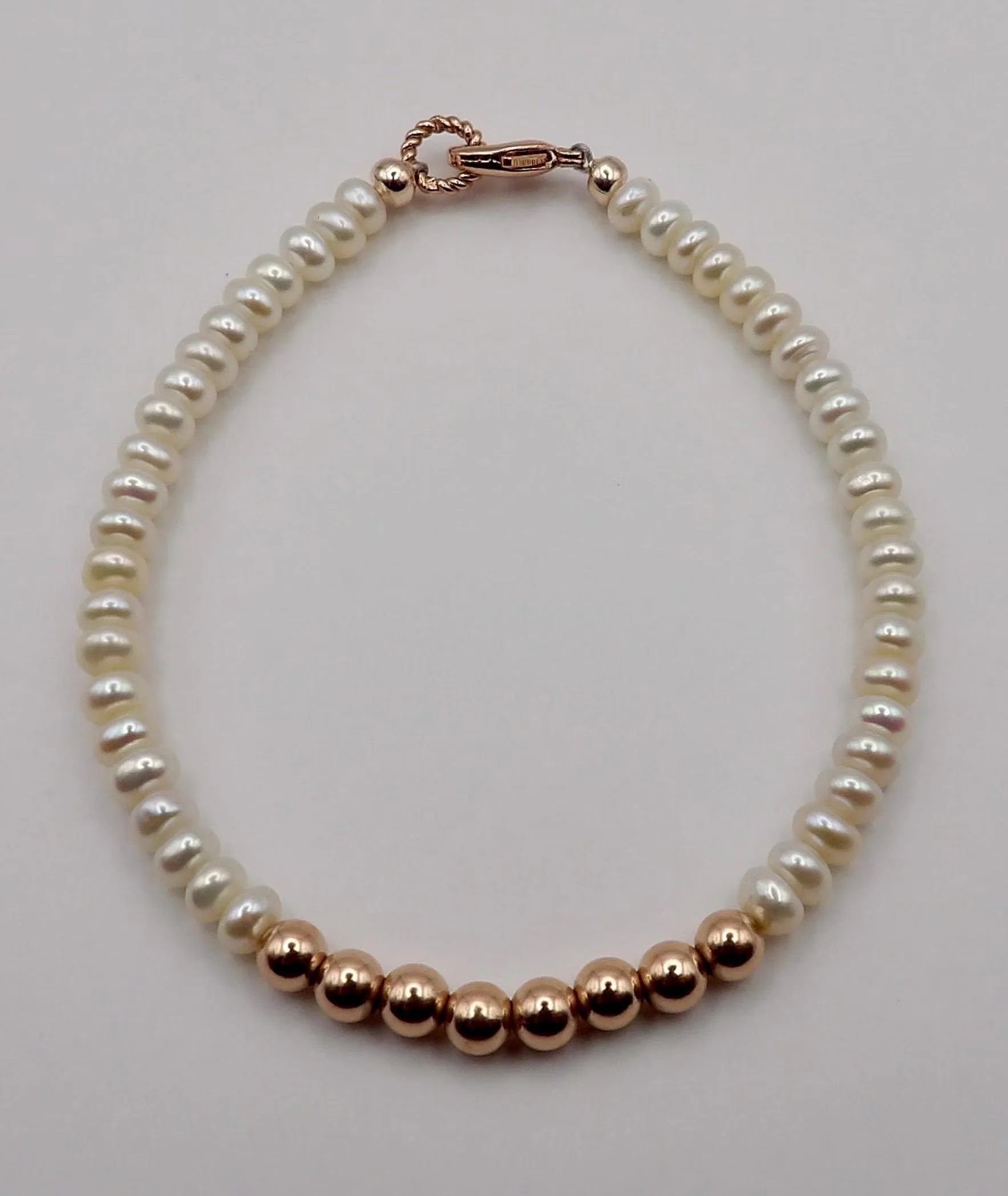 the classic romantic bracelet styled on a soft linen background to showcase its light-catching pearls and rose gold beads.