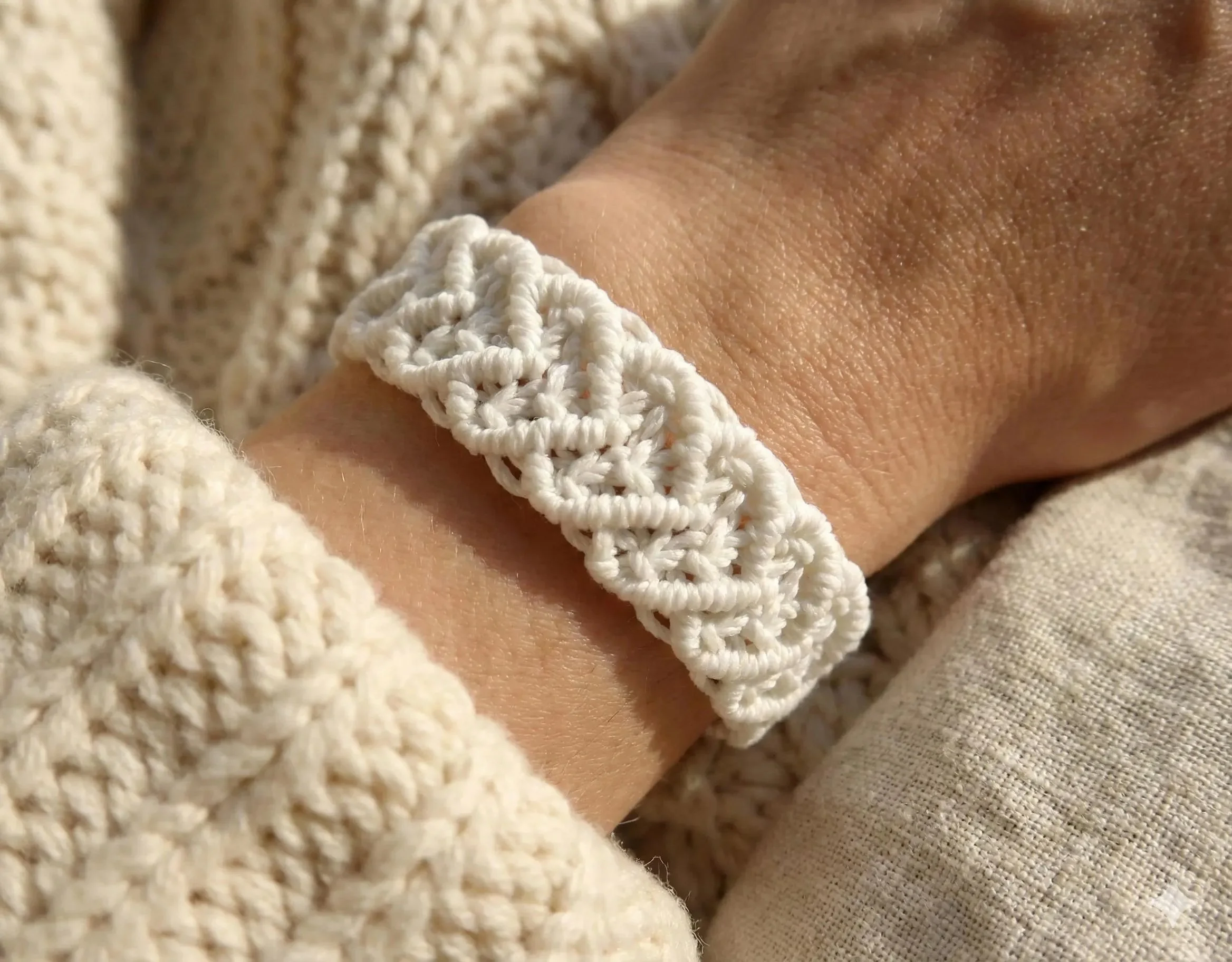 cream woven macramé heart cuff bracelet on a wrist with natural wood bead adjustable ties.