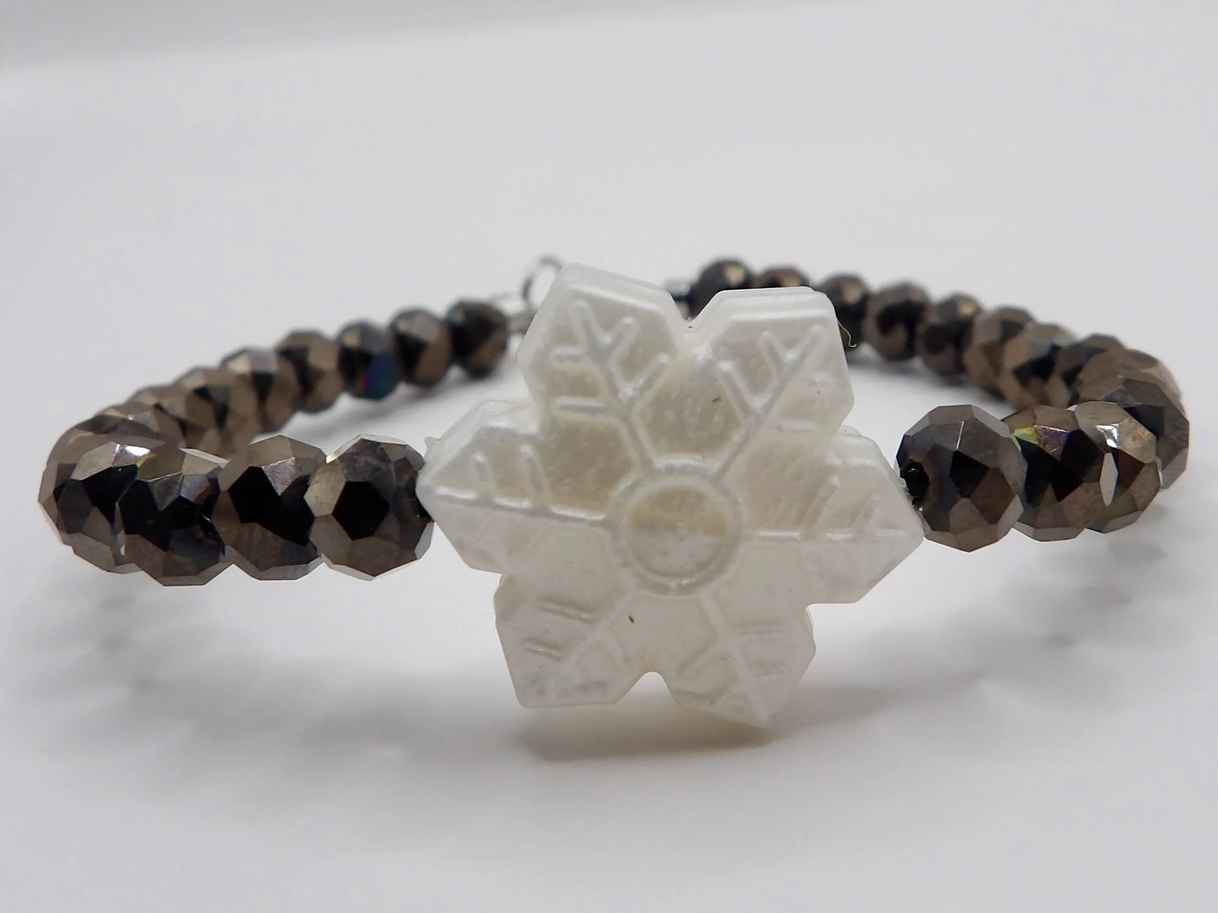handmade holiday bracelet with gunmetal faceted glass beads, a pearl silicone snowflake charm, and stainless steel clasp.