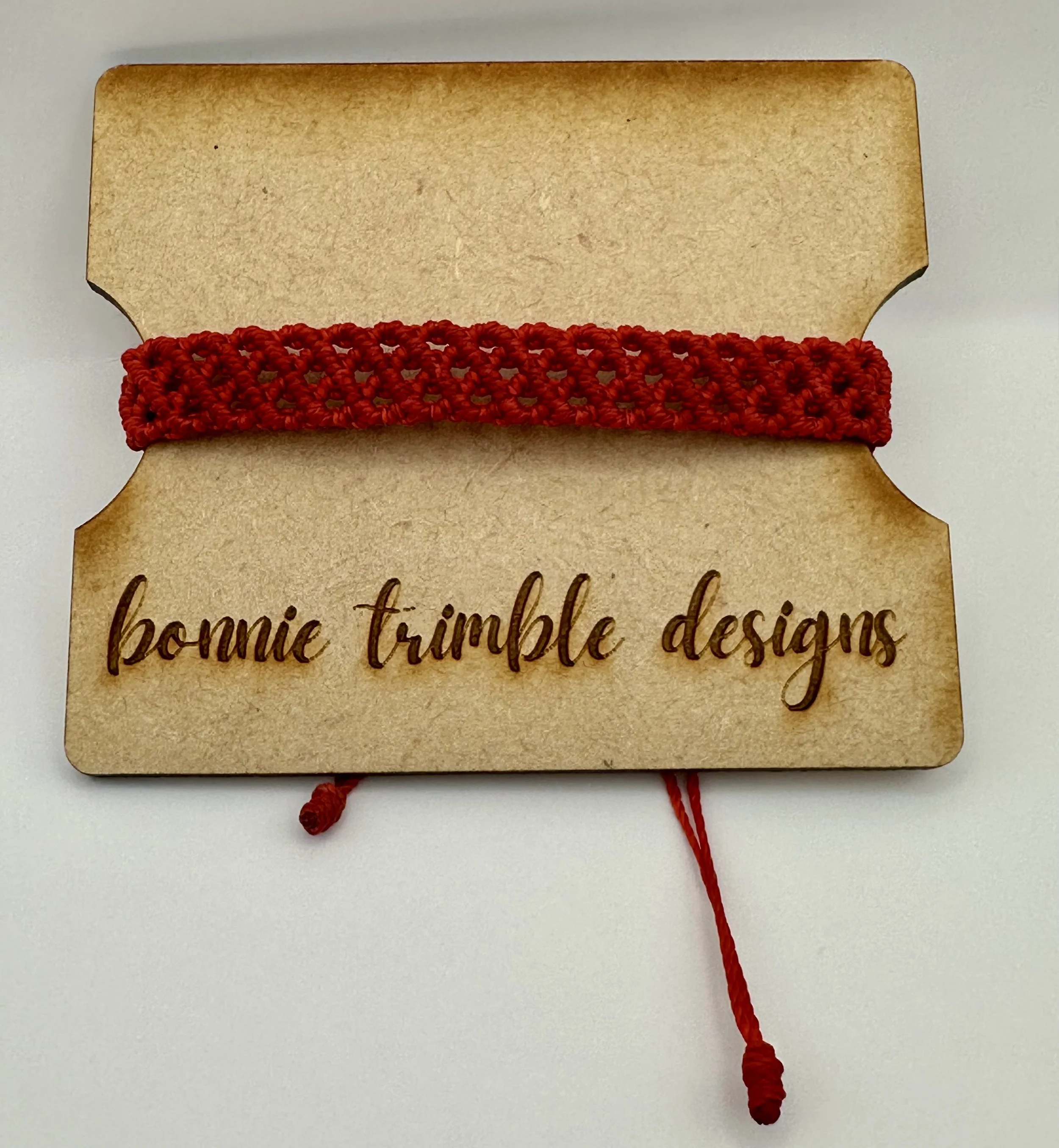 A macro close-up of the intricate micromacrame knotwork, showing the fine details of the woven red strands.