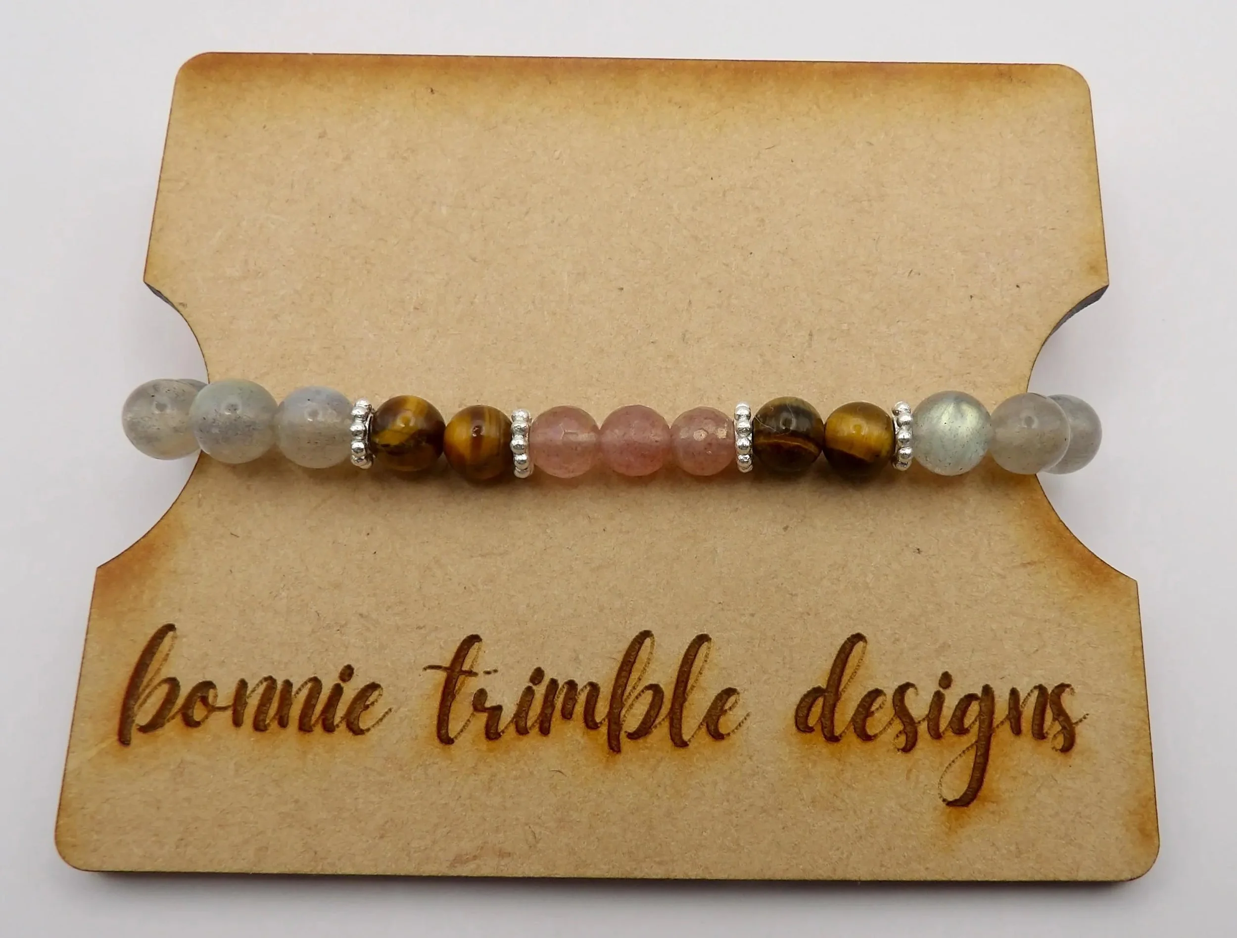 a powerful healing talisman bracelet showing the contrast between protective dark minerals, soothing pink quartz, and a polished silver floral spacer.