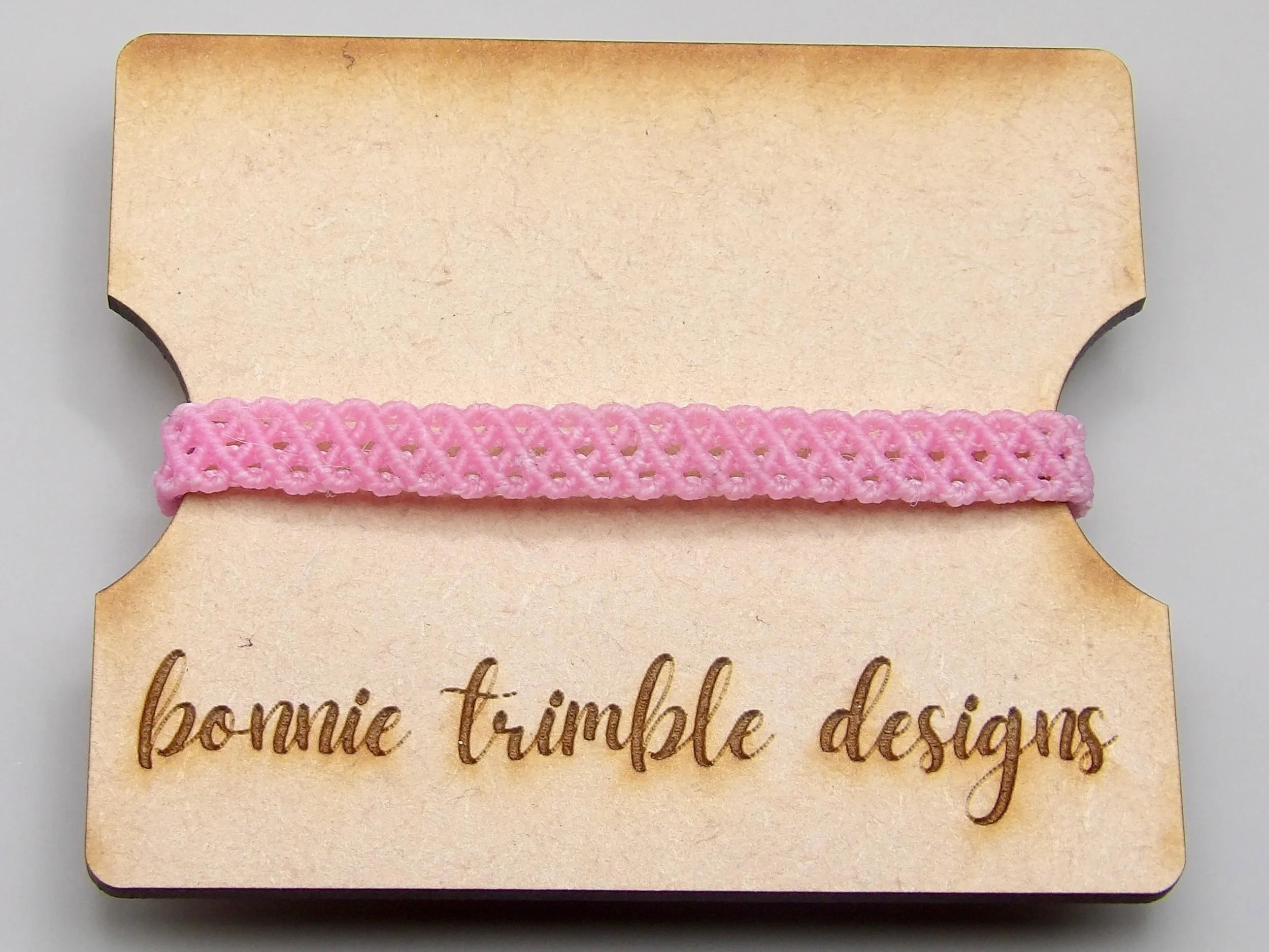 an adjustable pink anchor bracelet featuring a signature layered weave and tarnish-resistant 18k gold filled components.