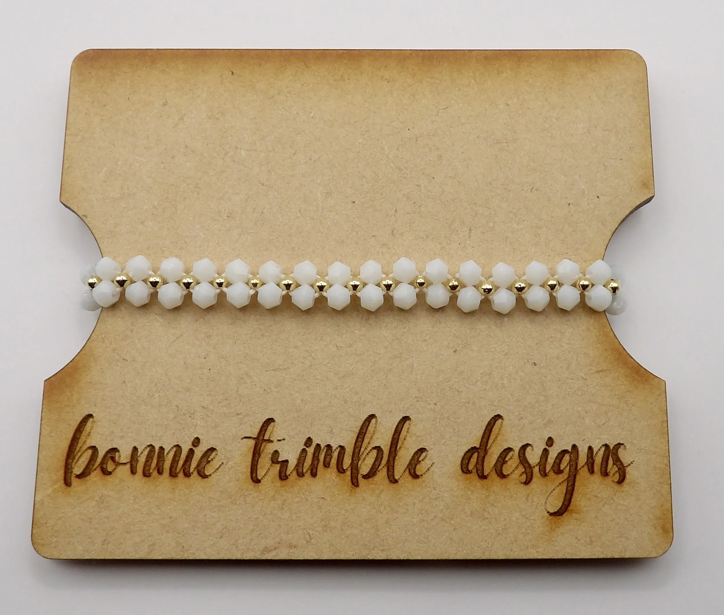 close-up detail of the cross-woven daisy chain pattern using white bicone crystals and 2mm gold beads.