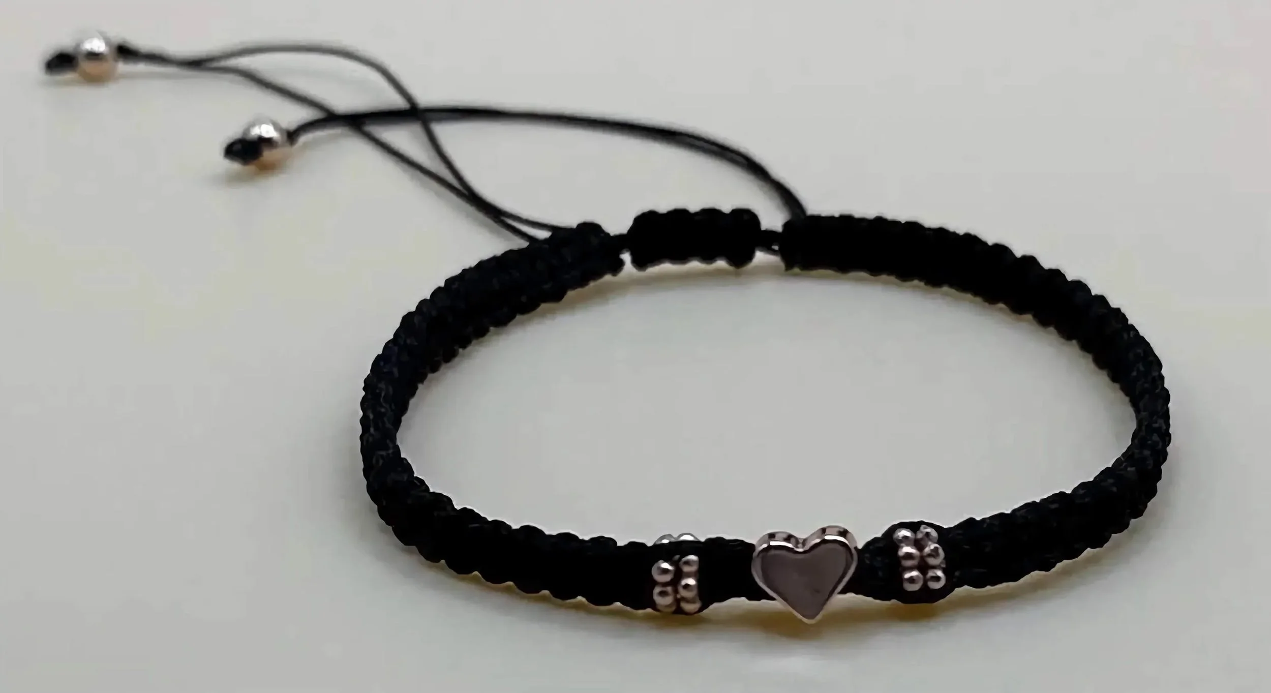 close-up of the chic minimalist bracelet highlighting the delicate heart detail and the clean, industrial sliding knot finish.