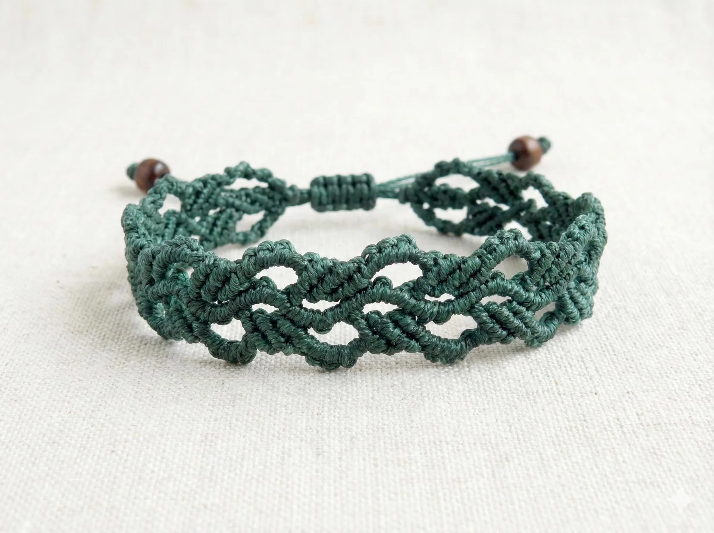 Forest green macramé bracelet with a botanical weave and stainless steel daisy spacers.