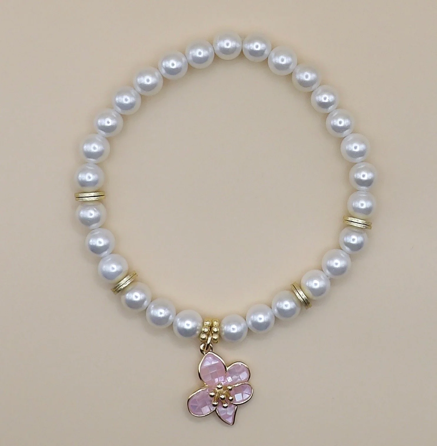 handmade 18k gold and mother of pearl beaded bracelet featuring a central pink flower charm nestled between gold daisy spacers.