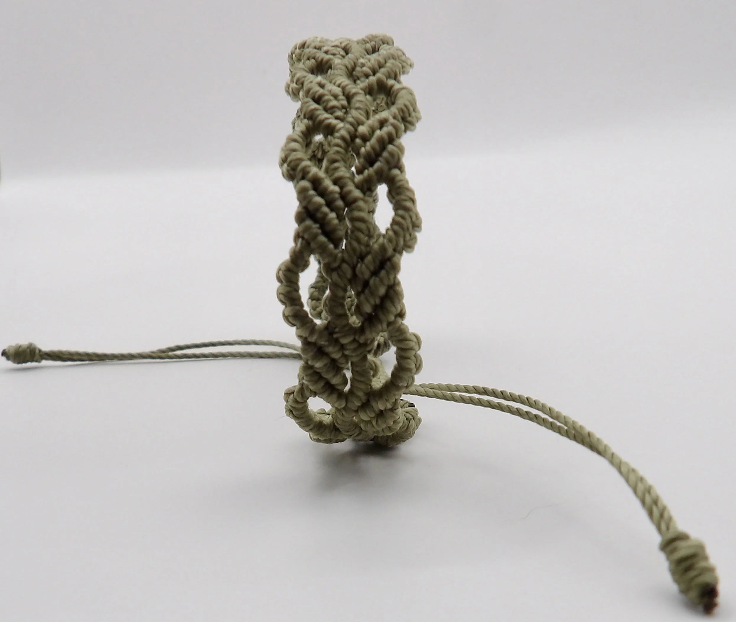 view of the adjustable sliding knot closure on the handmade green ivy leaf waxed cord macrame bracelet.