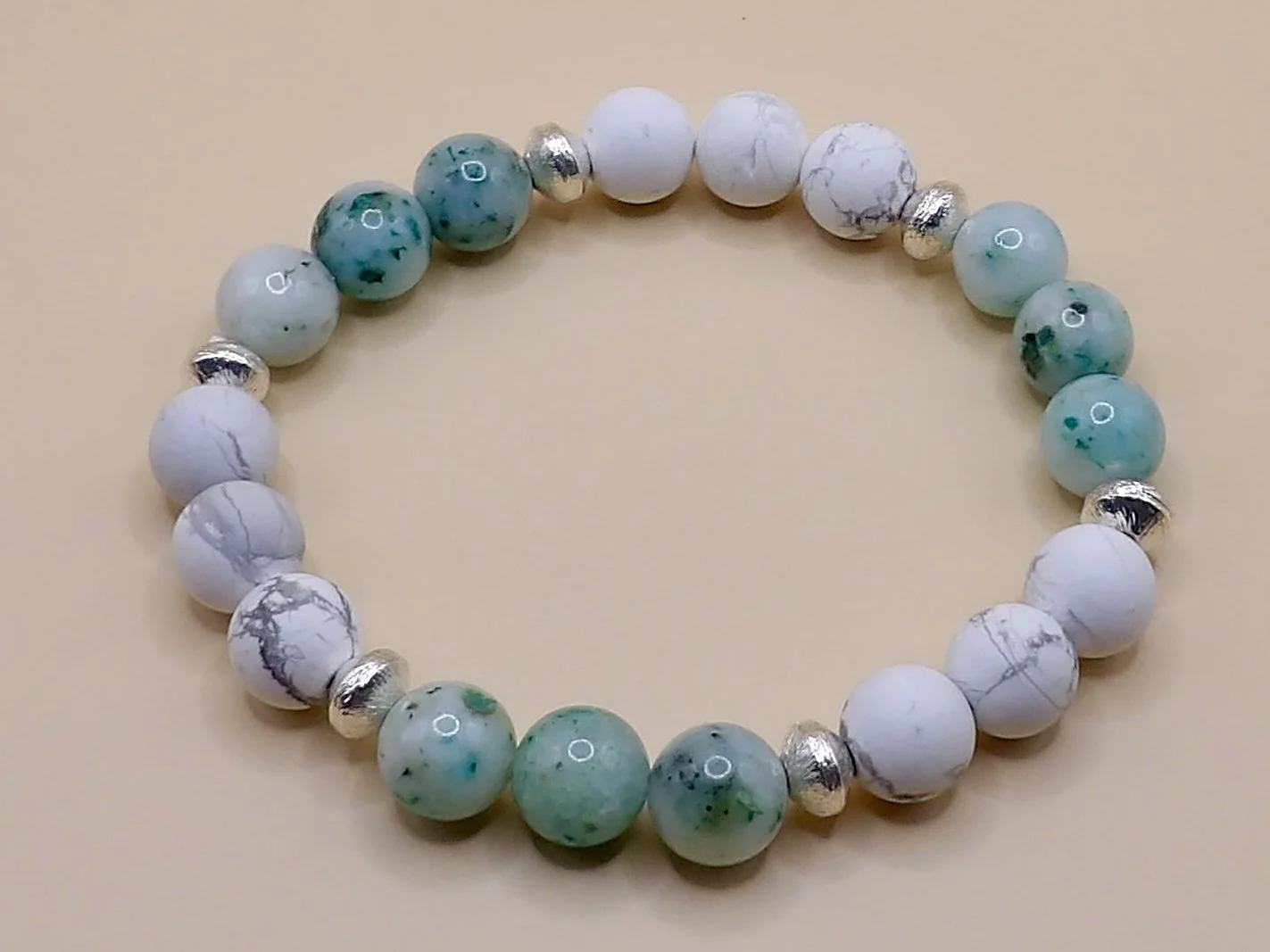 handmade stretch bracelet with 8mm matte howlite, 8mm green chrysocolla, and 6mm brushed sterling silver saucer beads in a repeating pattern.