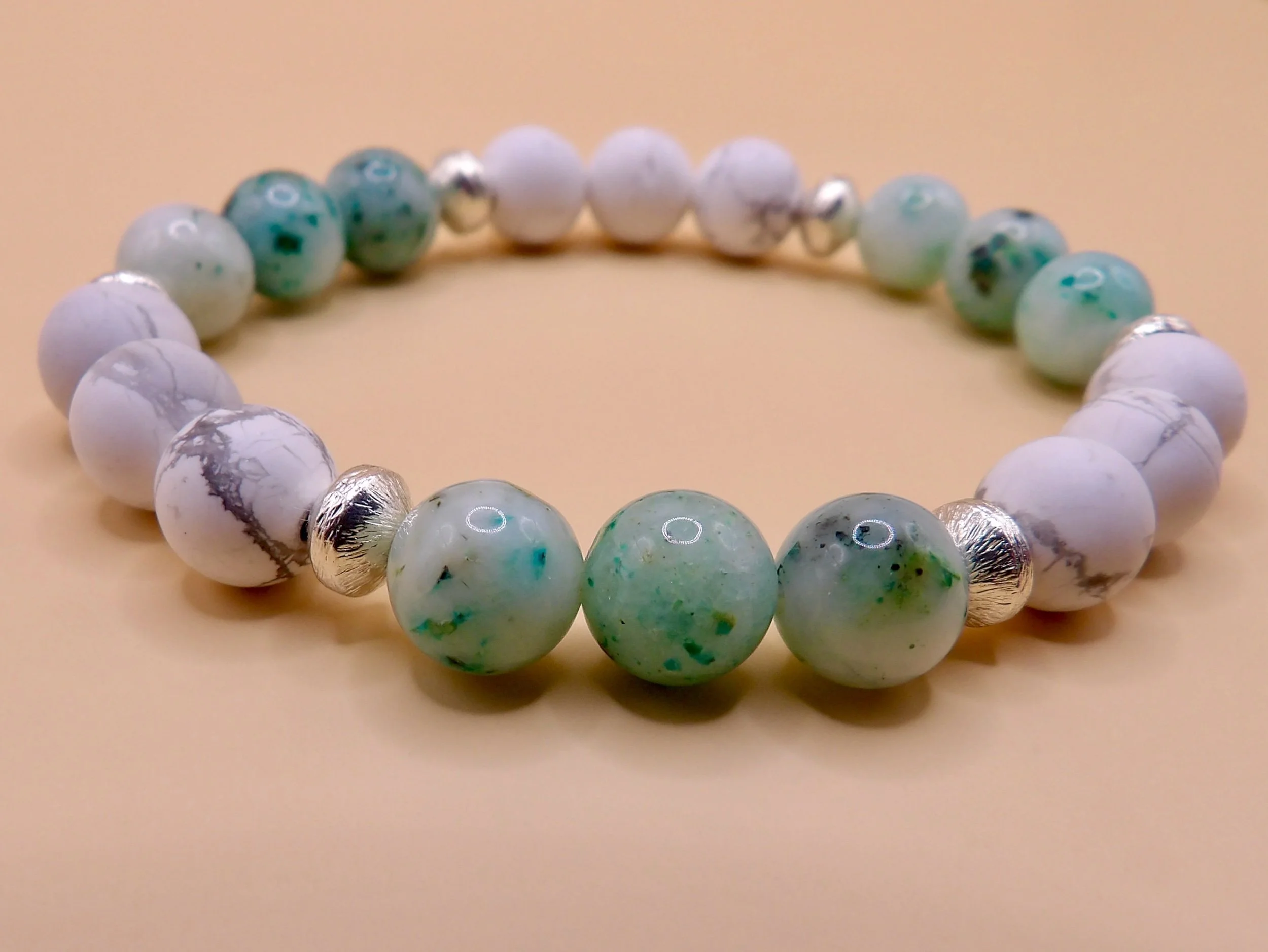 person wearing the howlite and chrysocolla beaded stretch bracelet, stacked with other jewelry, showing its boho style.