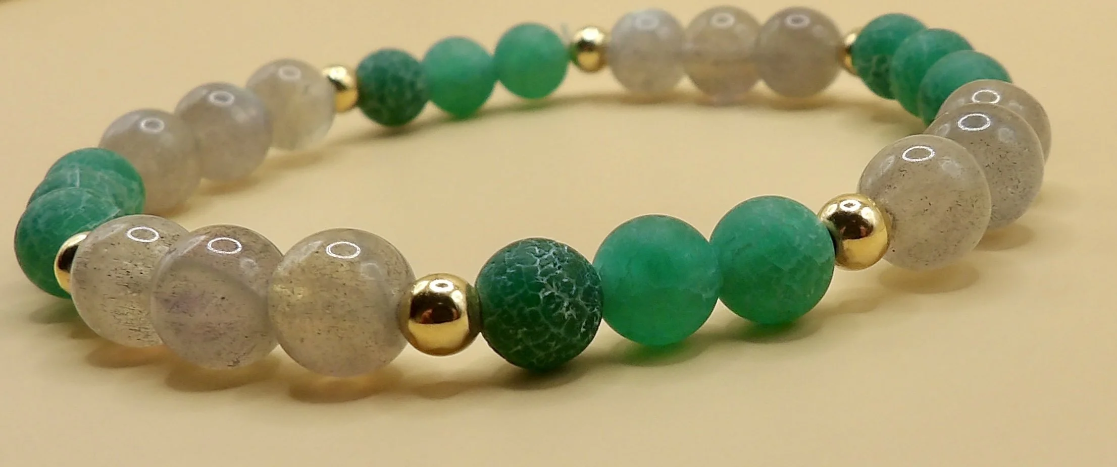 detail view capturing the blue and green flash (labradorescence) of the 6mm smooth round labradorite beads on the handmade stretch bracelet.