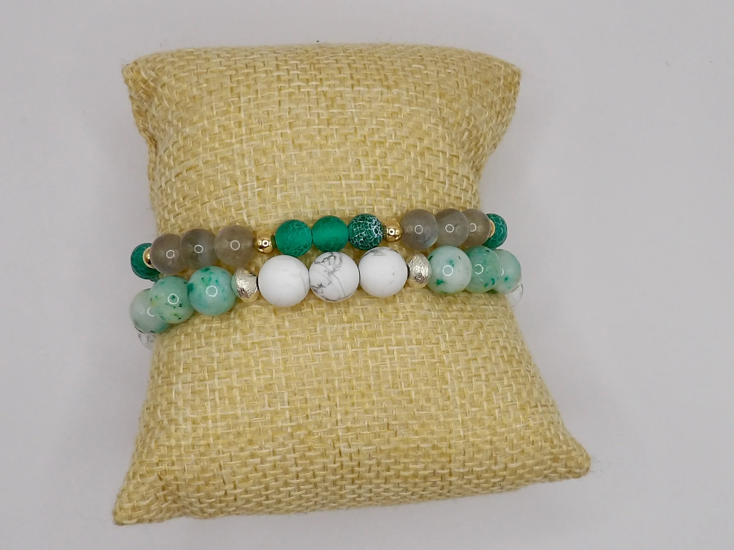 person wearing the green fire cracked agate and labradorite gemstone bracelet stacked with other bracelets, showing its 18k gold accents.