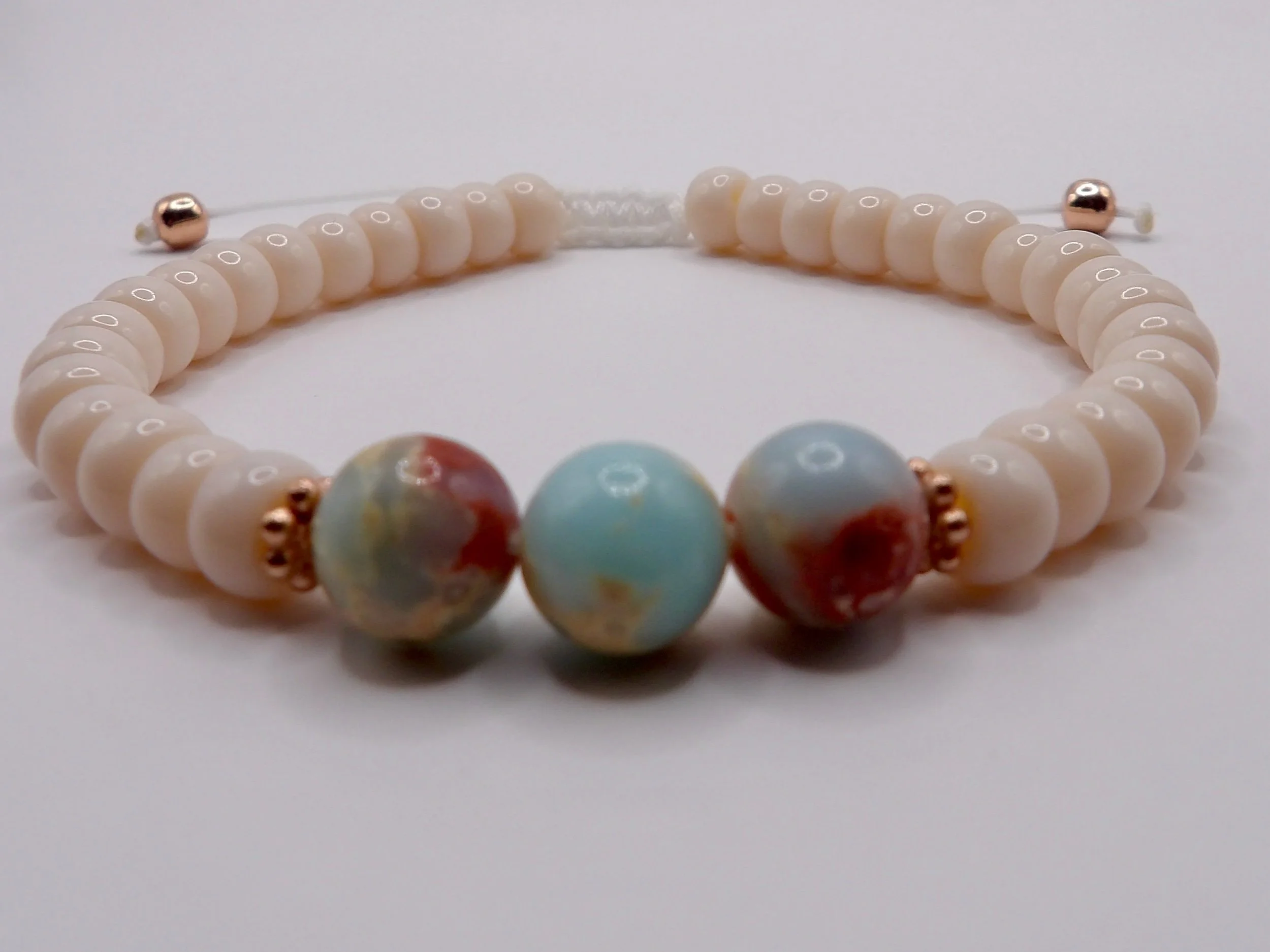 view of the adjustable macrame sliding knot on the white nylon cord, showing the two 4mm 14k solid rose gold tail beads.