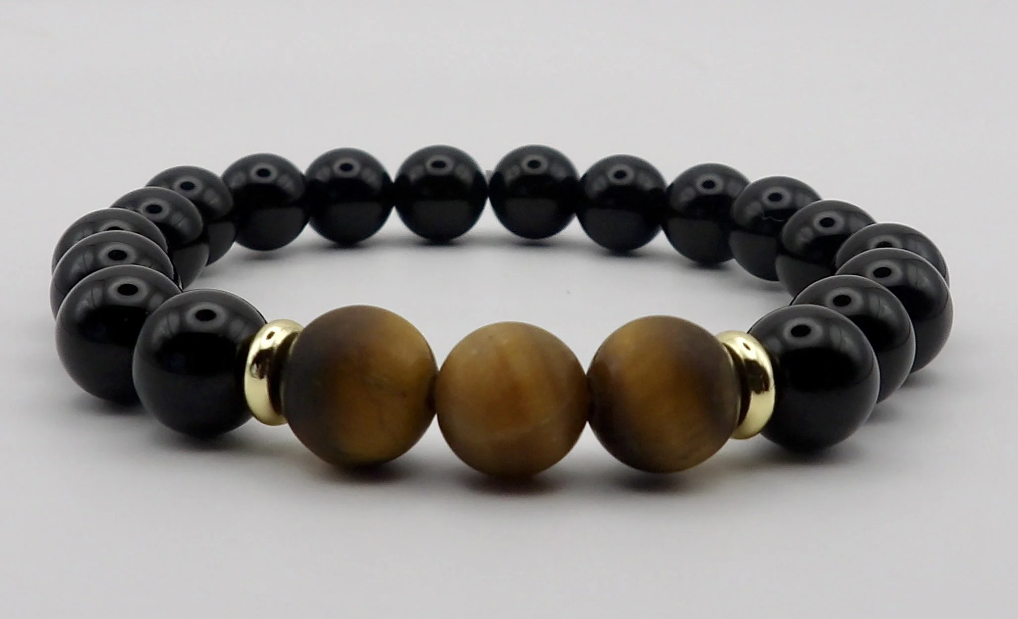handmade 18k gold stretch bracelet set showing two inverse designs of matte tigers eye and polished black onyx with 18k gold heishi accents.