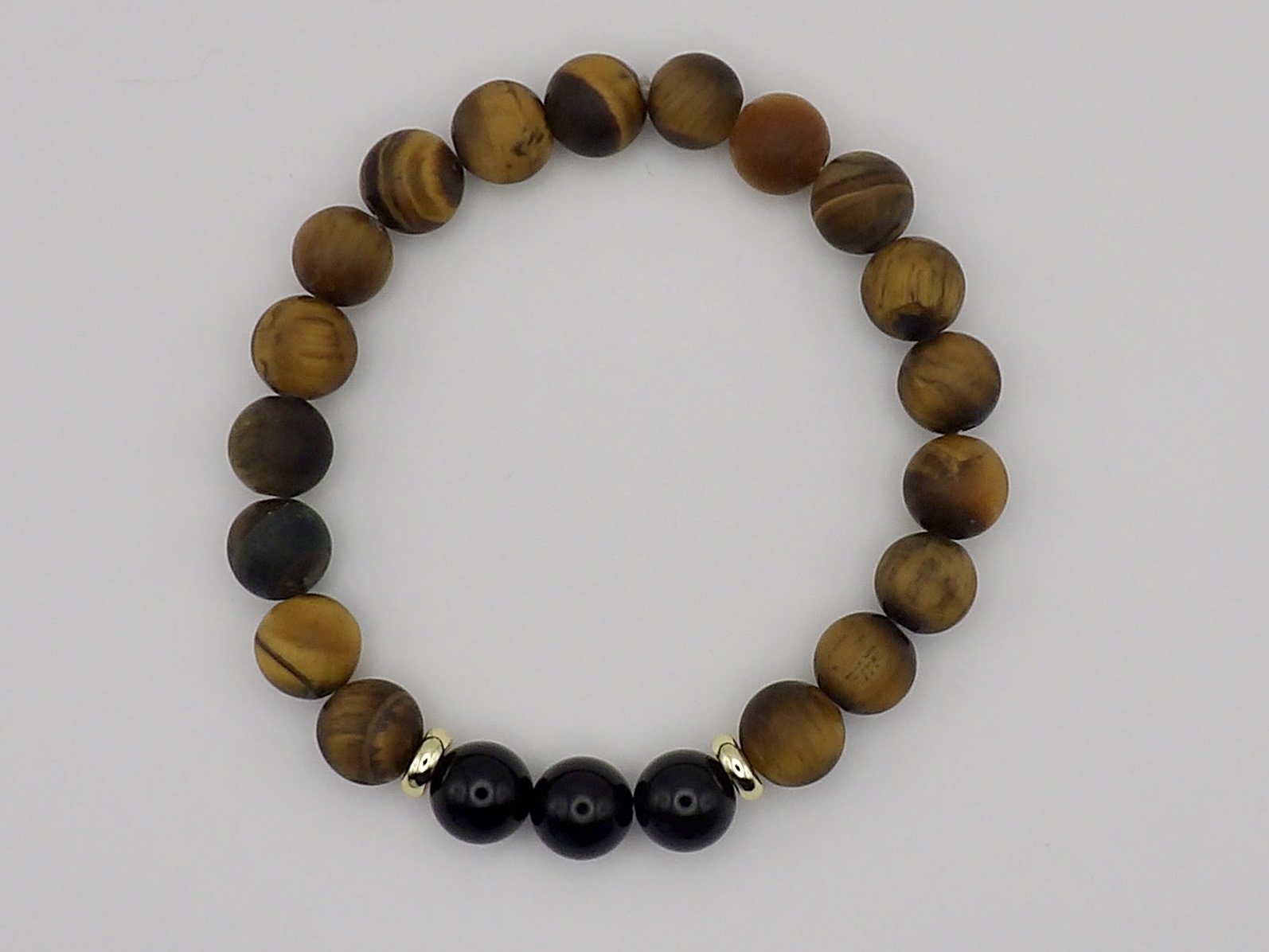 person wearing the full 2-piece stack of 18k gold, onyx, and tigers eye inverse bracelets, showing matte and polished contrast.