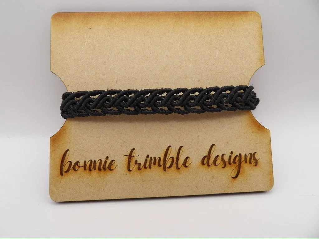 person wearing the minimalist black scrollwork macrame bracelet, showing its adjustable fit and elegant texture.