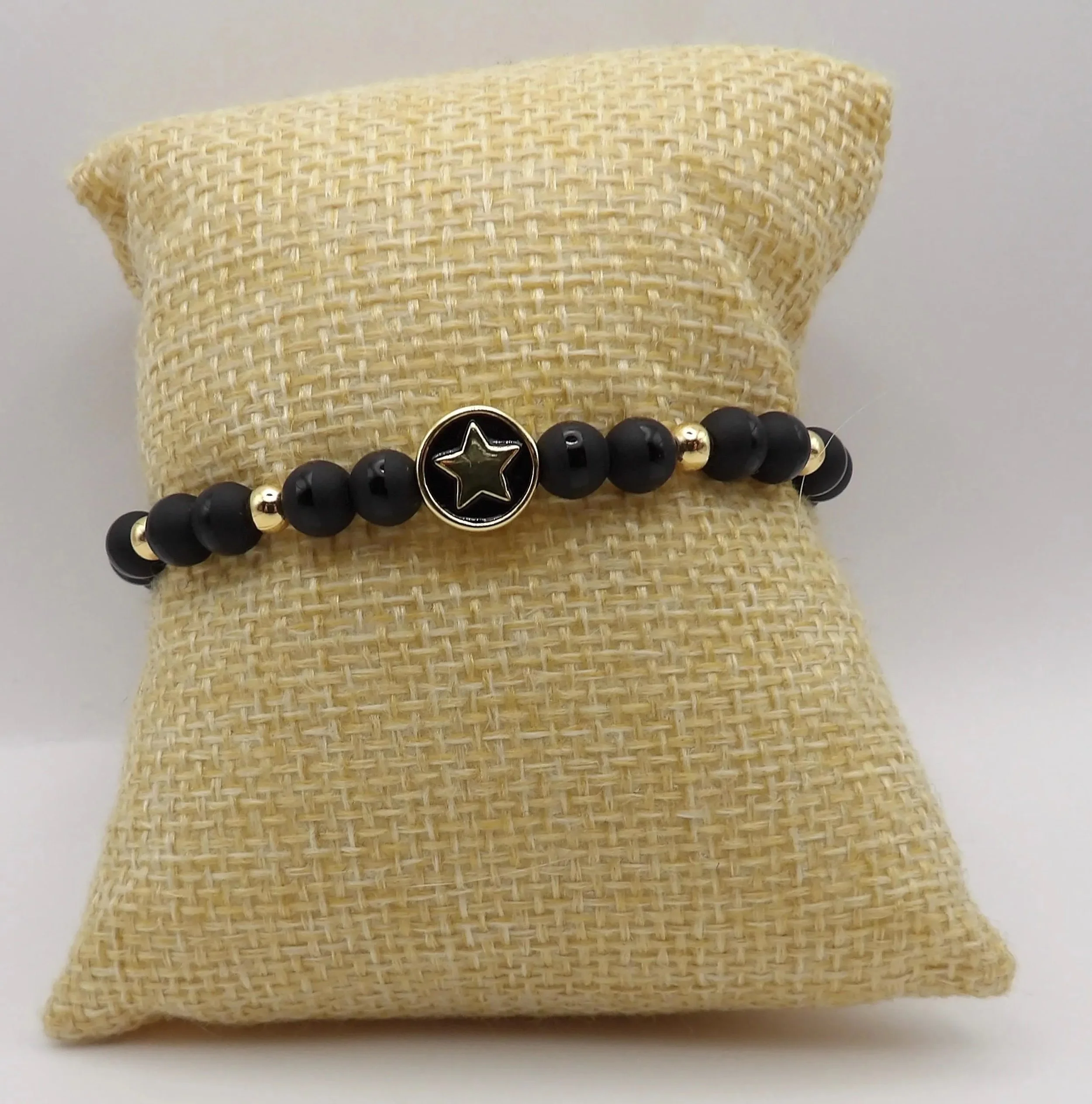 detailed view of the high-quality 18k gold-plating on the star charm alongside a seamless blend of matte and polished black onyx.