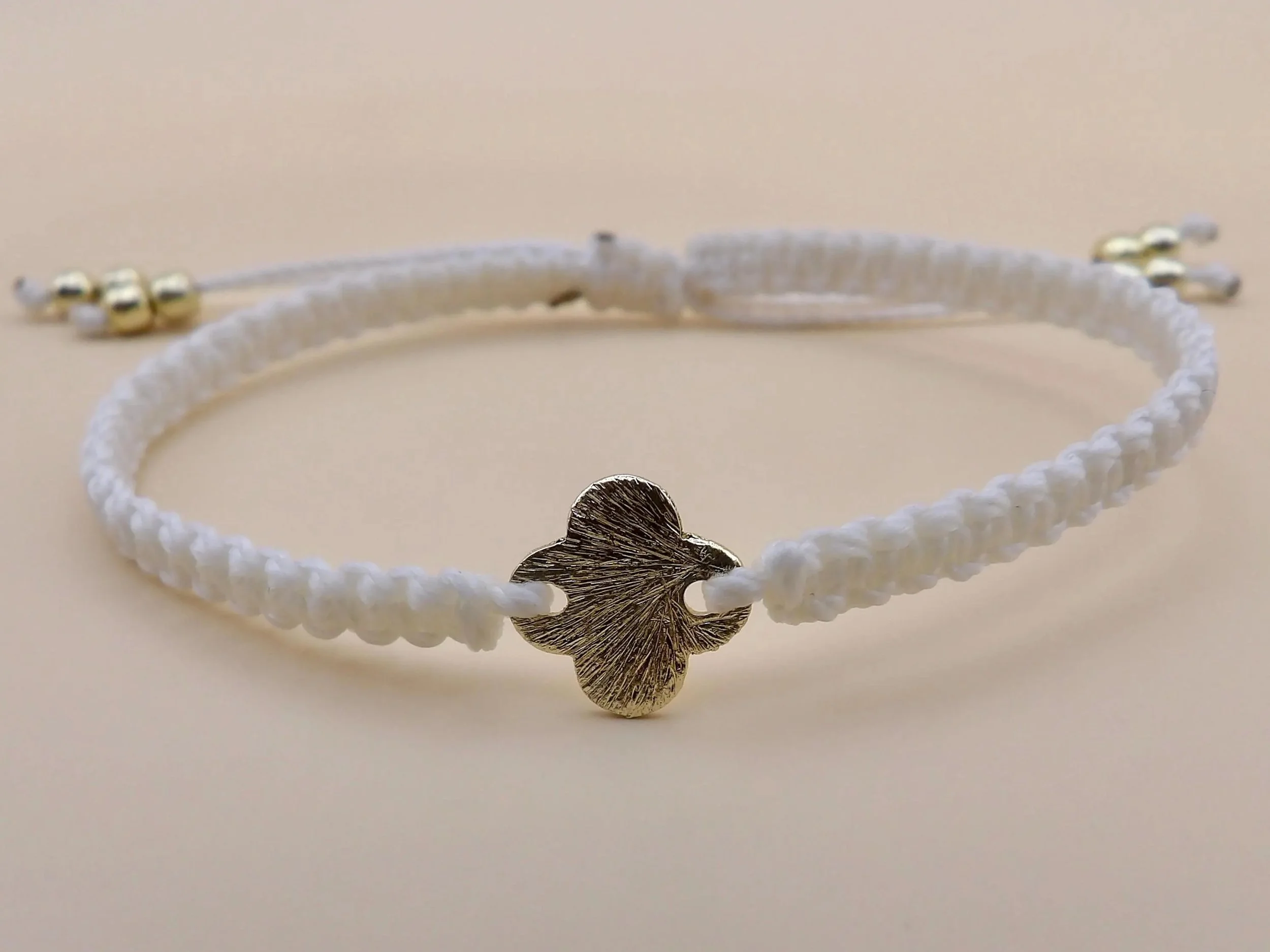 a versatile, unisex faith talisman featuring a premium brushed gold finish and a lightweight, waterproof beige cord weave.