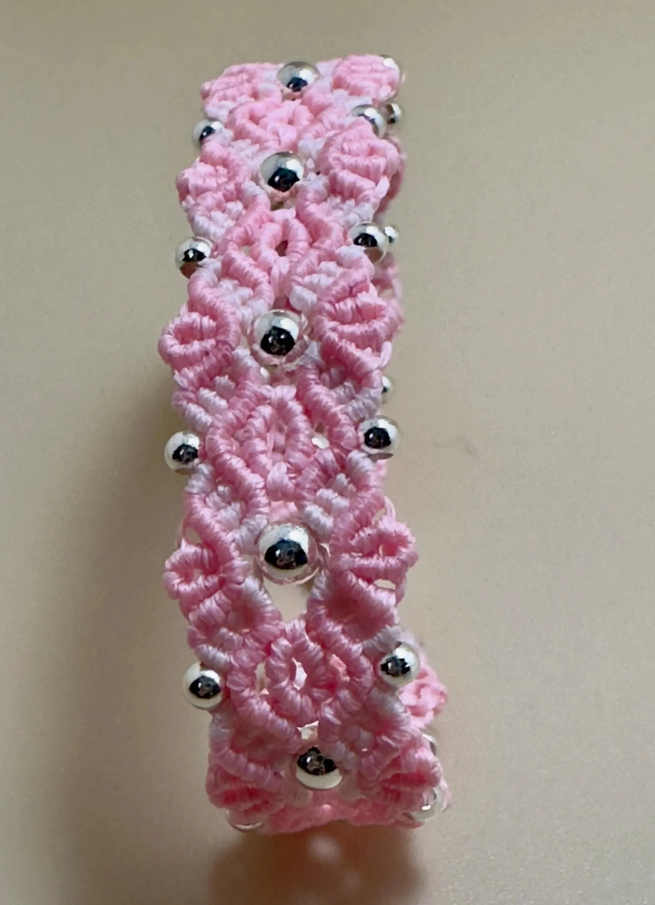 an intricate pink flower-motif bracelet handcrafted with ultra-fine cord and premium .925 silver focal beads.