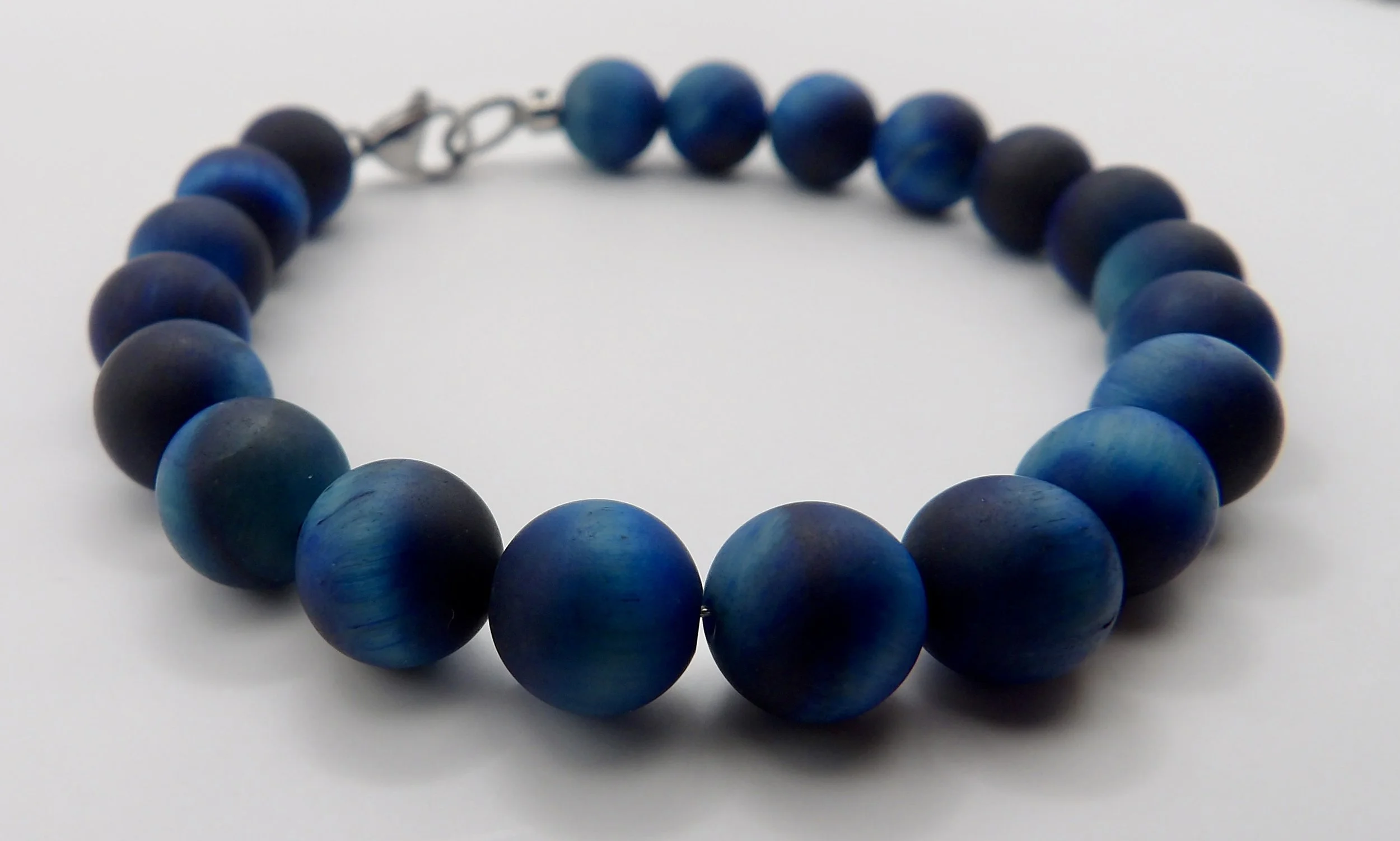 close-up detail showing the matte finish and subtle chatoyant flash of the blue tiger's eye beads.