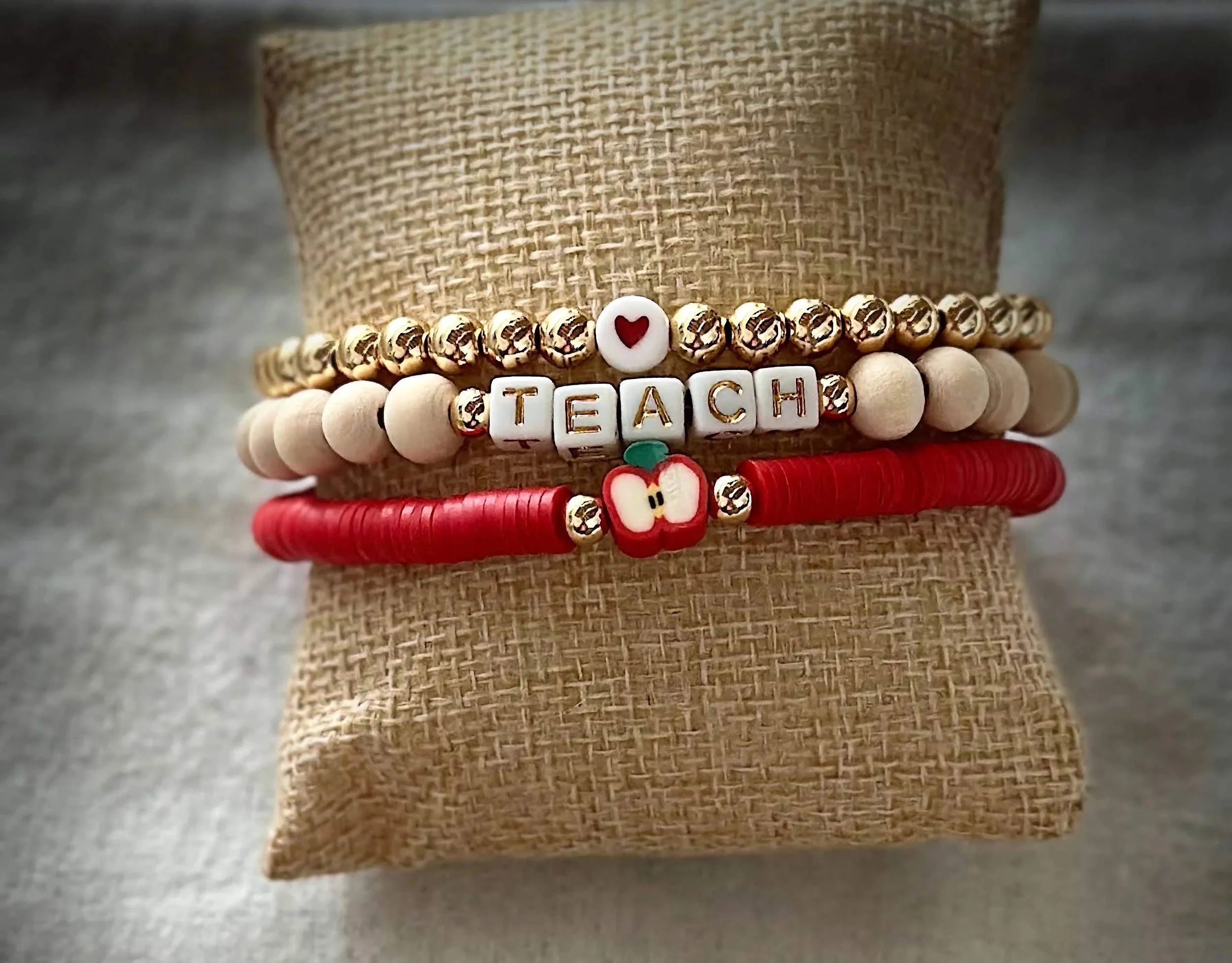 product image of a handmade bracelet for teachers, with a heart, apple, and teach spelled out in beads