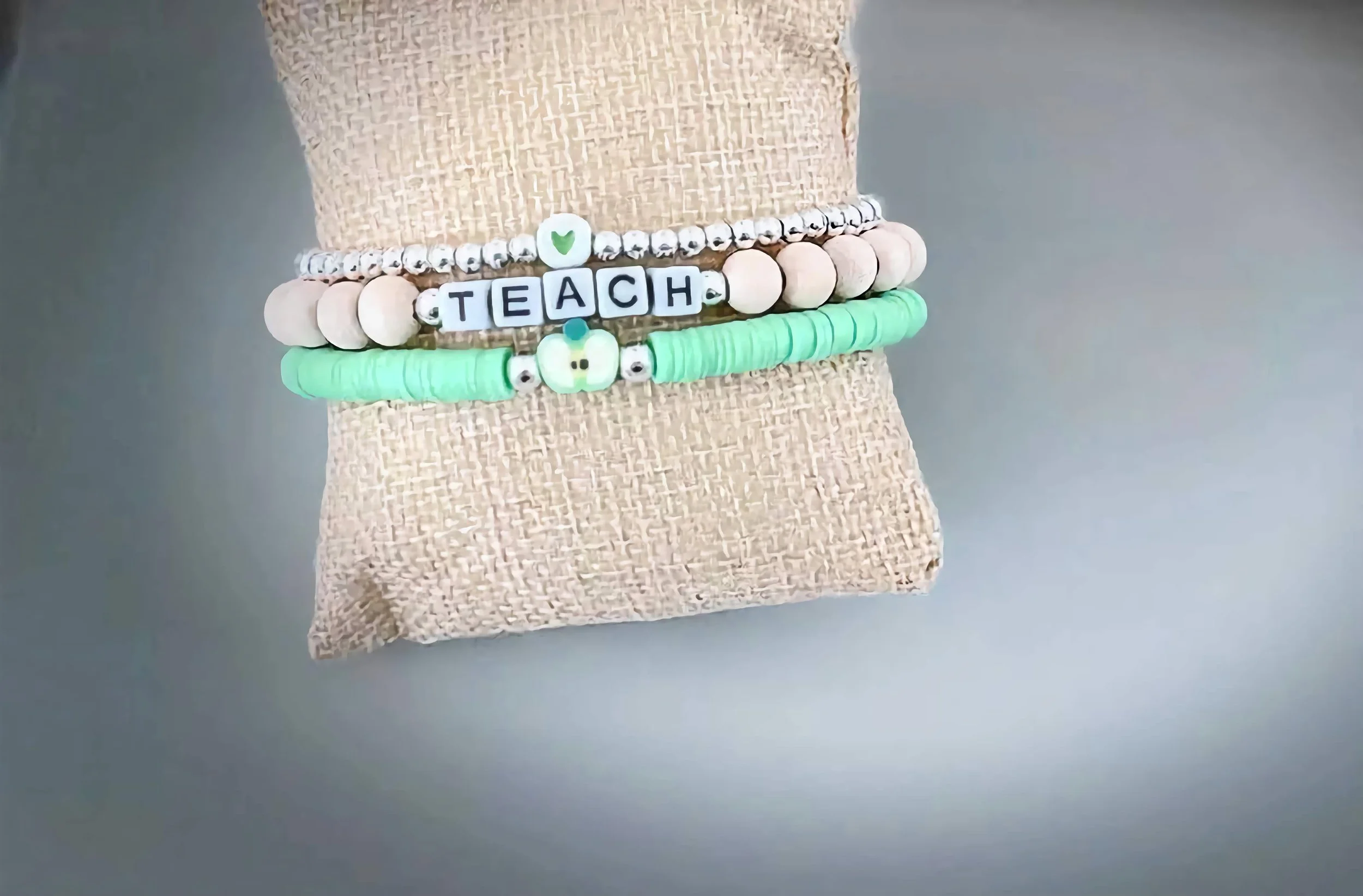 product image of a handmade bracelet for teachers, with a heart, apple, and teach spelled out in beads