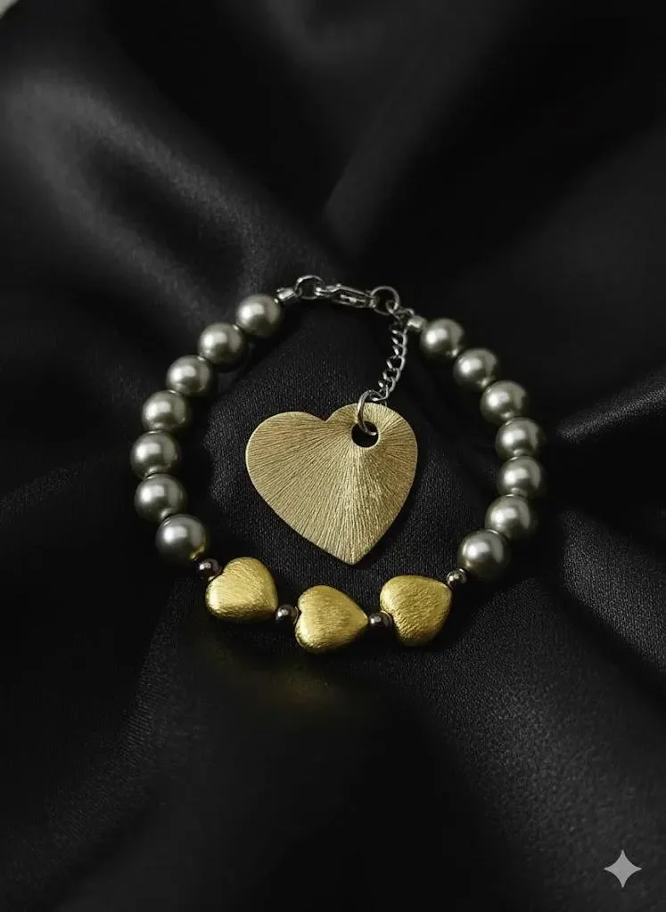 a moody, mixed-metal jewelry piece showing the contrast between dark gunmetal pearls and warm brushed gold heart charms.