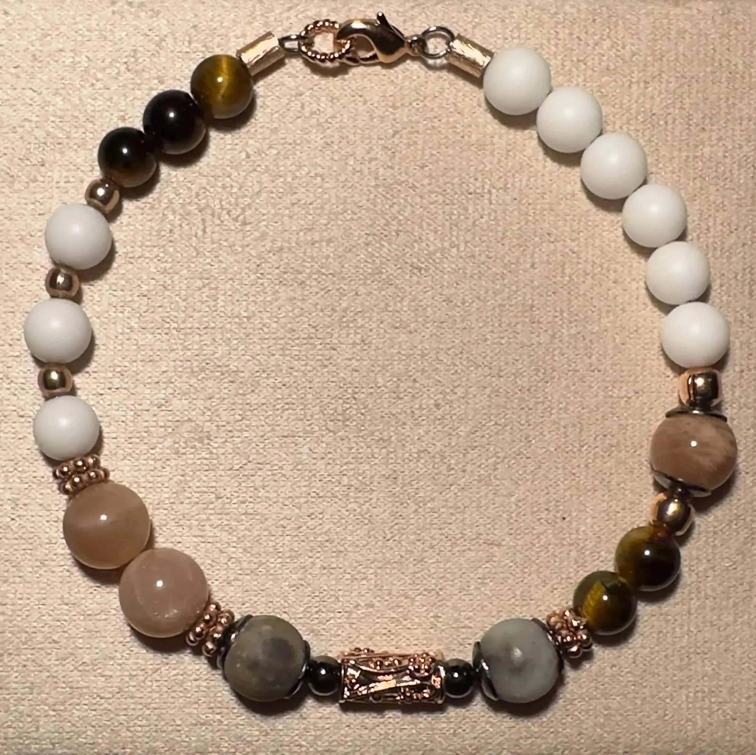 a multi-gemstone stacking bracelet designed with an intentional, artistic asymmetrical layout and metallic rose gold beads.