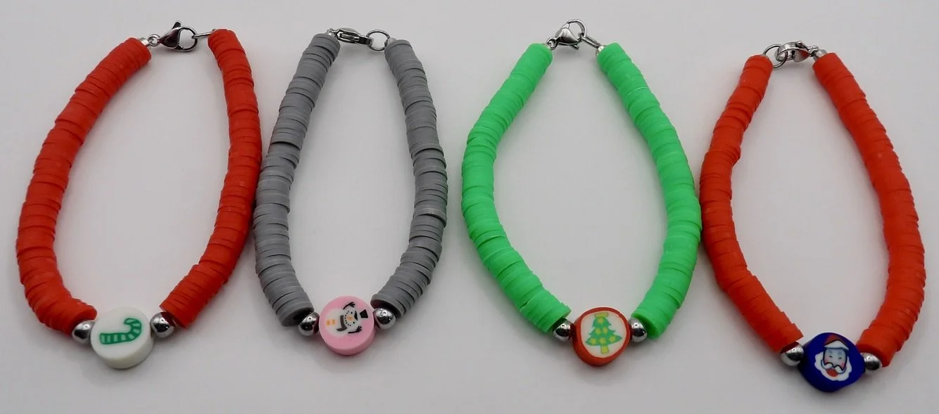 handmade christmas bracelet with green polymer clay heishi beads, a white/red christmas tree focal bead, and stainless steel clasp.