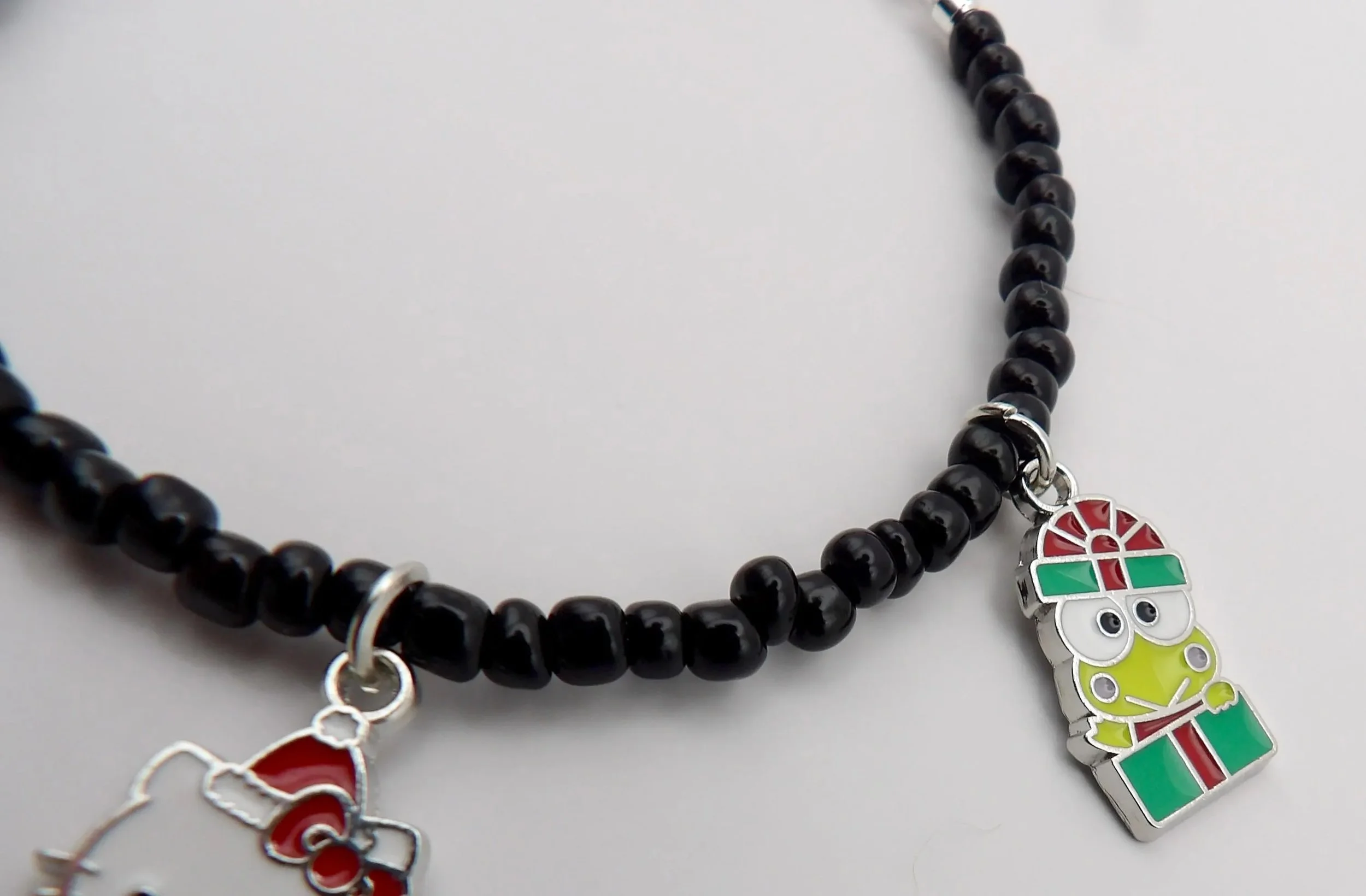 a luxury christmas-themed hello kitty bracelet showing shimmering sterling silver holiday charms against high-shine black beads.