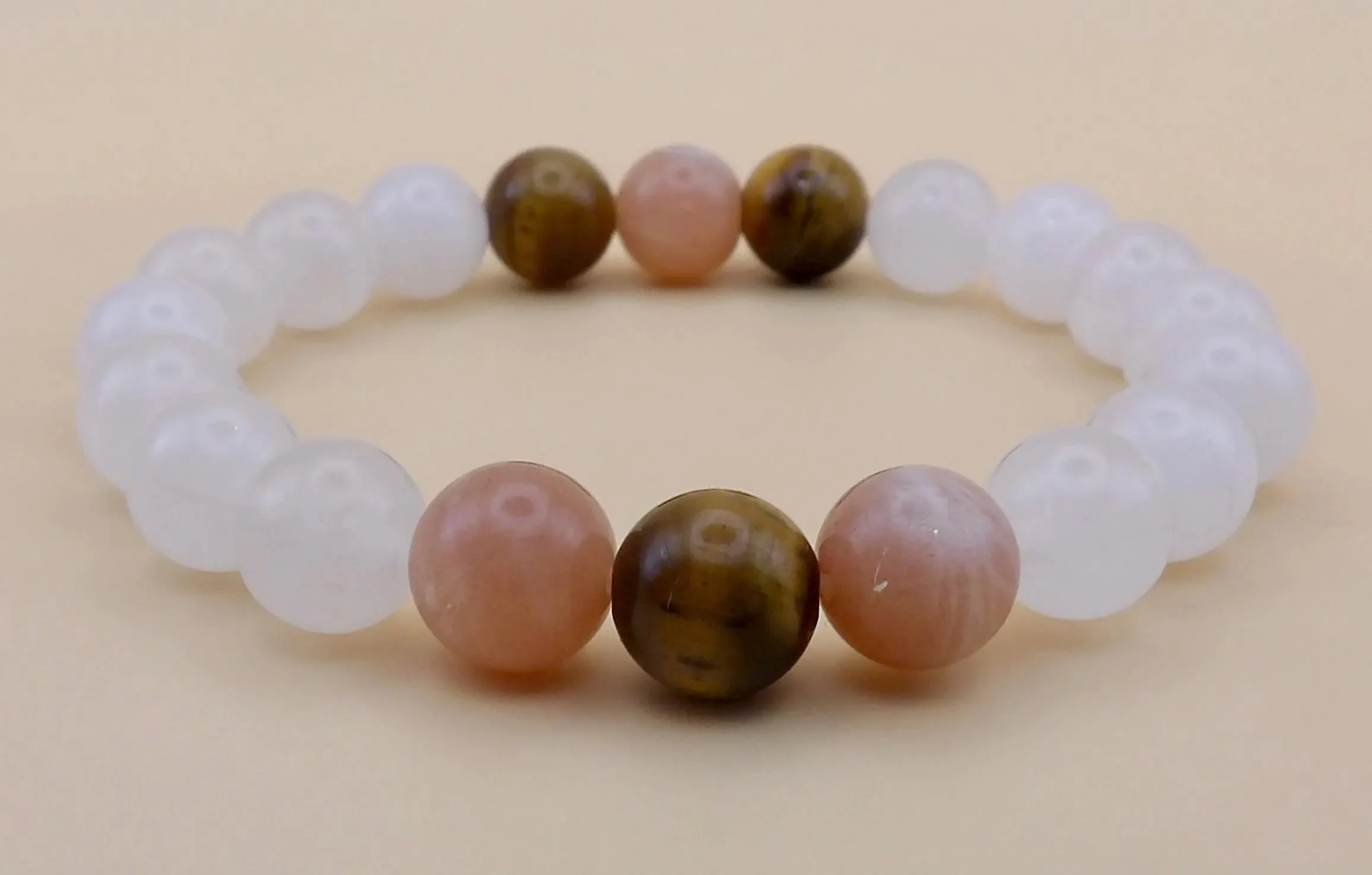 a sophisticated gemstone stretch bracelet showing the elegant texture transition between polished jade, reflective sunstone flecks, and silky tiger's eye bands.