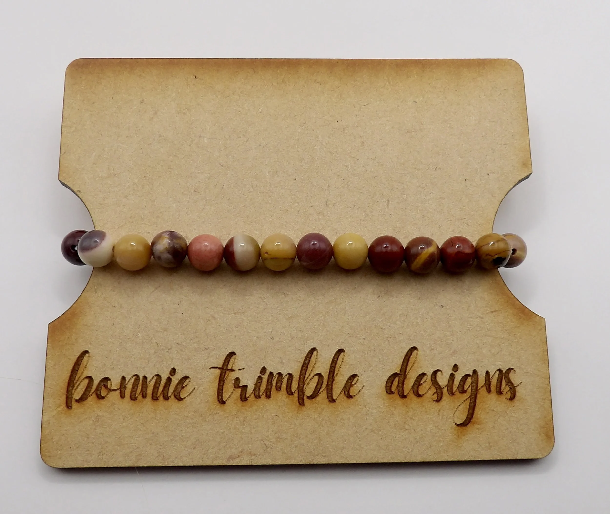 person wearing the warm earth-tone mookaite jasper stretch bracelet, stacked with other dainty boho jewelry.