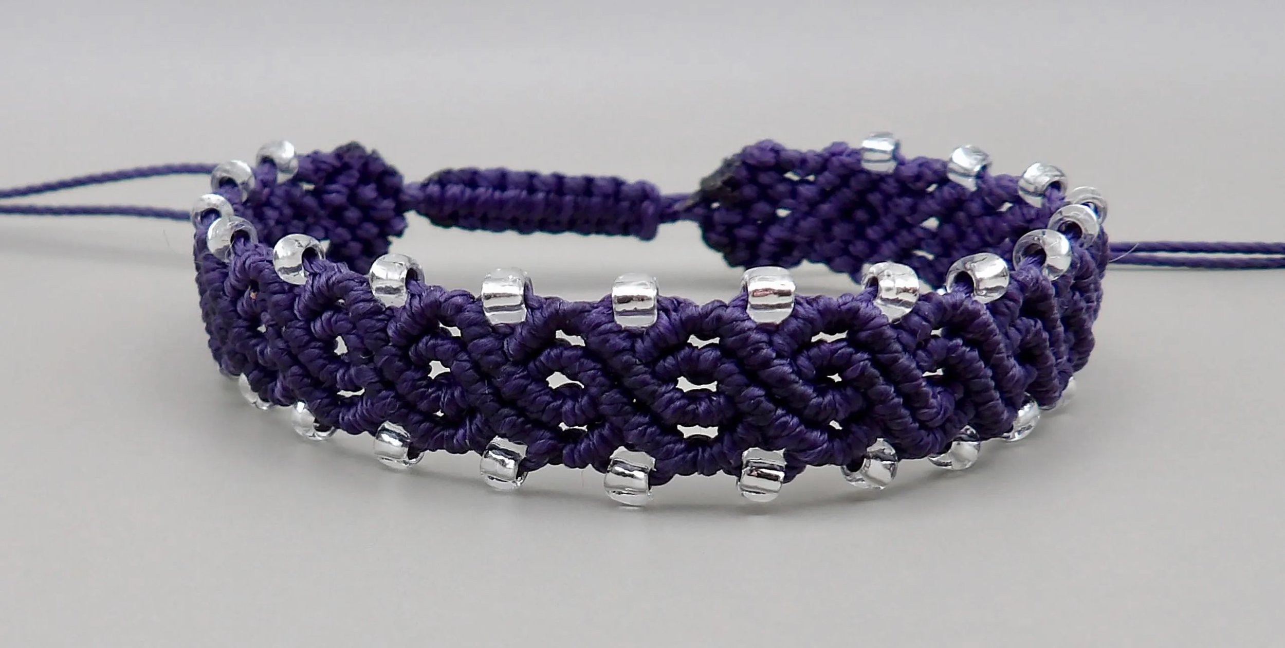 a versatile and lightweight custom-color bracelet featuring a signature scalloped macramé edge and silver-lined accents.