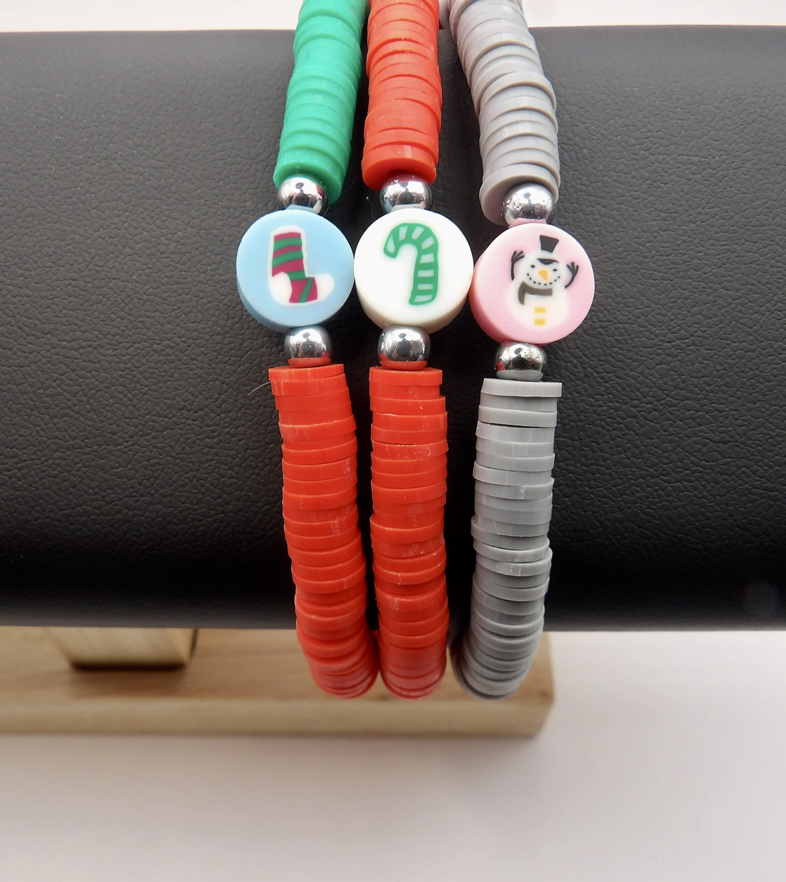 handmade christmas bracelet with gray polymer clay heishi beads, a pink snowman focal bead, and stainless steel clasp.